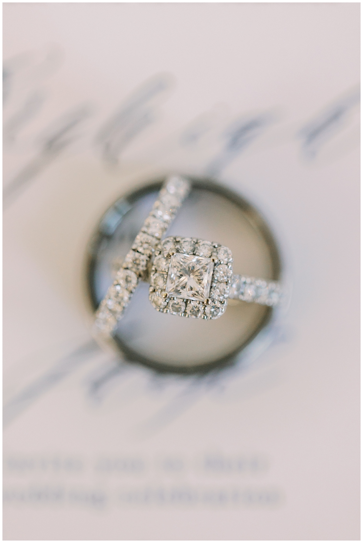 platinum wedding rings on top of white wedding invitation