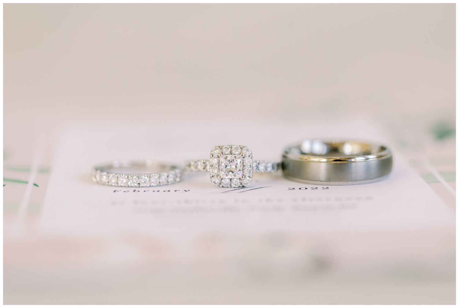 platinum wedding rings laying on The Springs Wallisville Wedding invitation