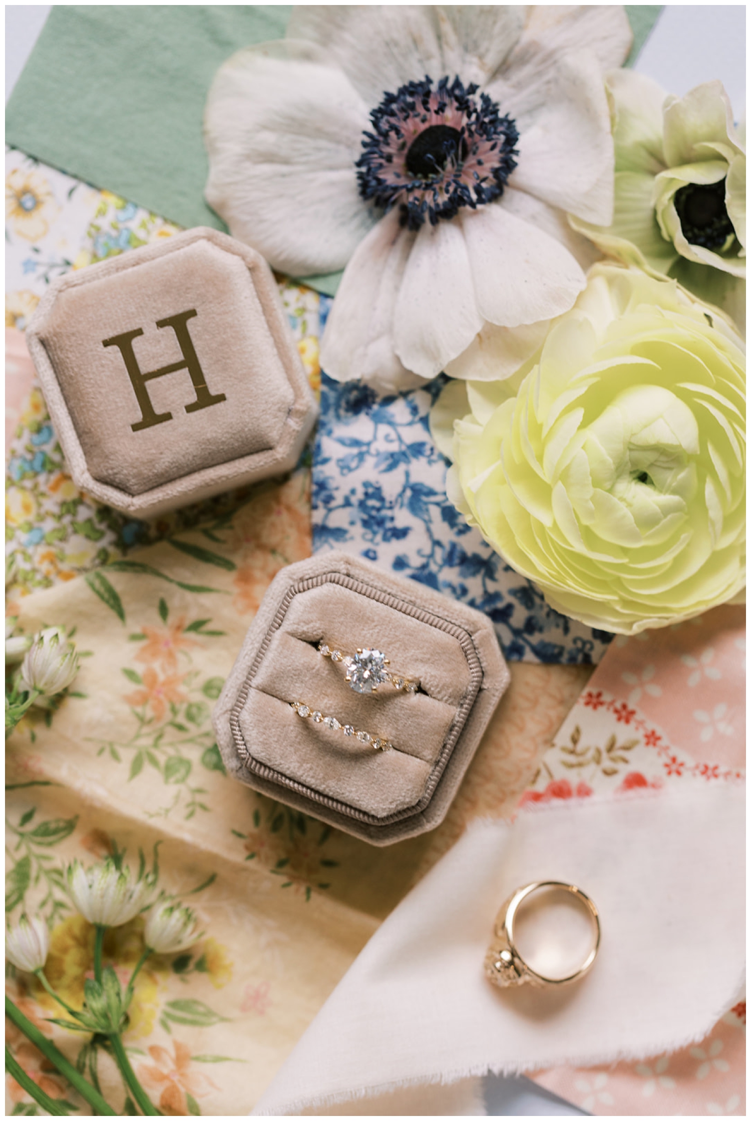 taupe ring box with H and wedding rings on florals