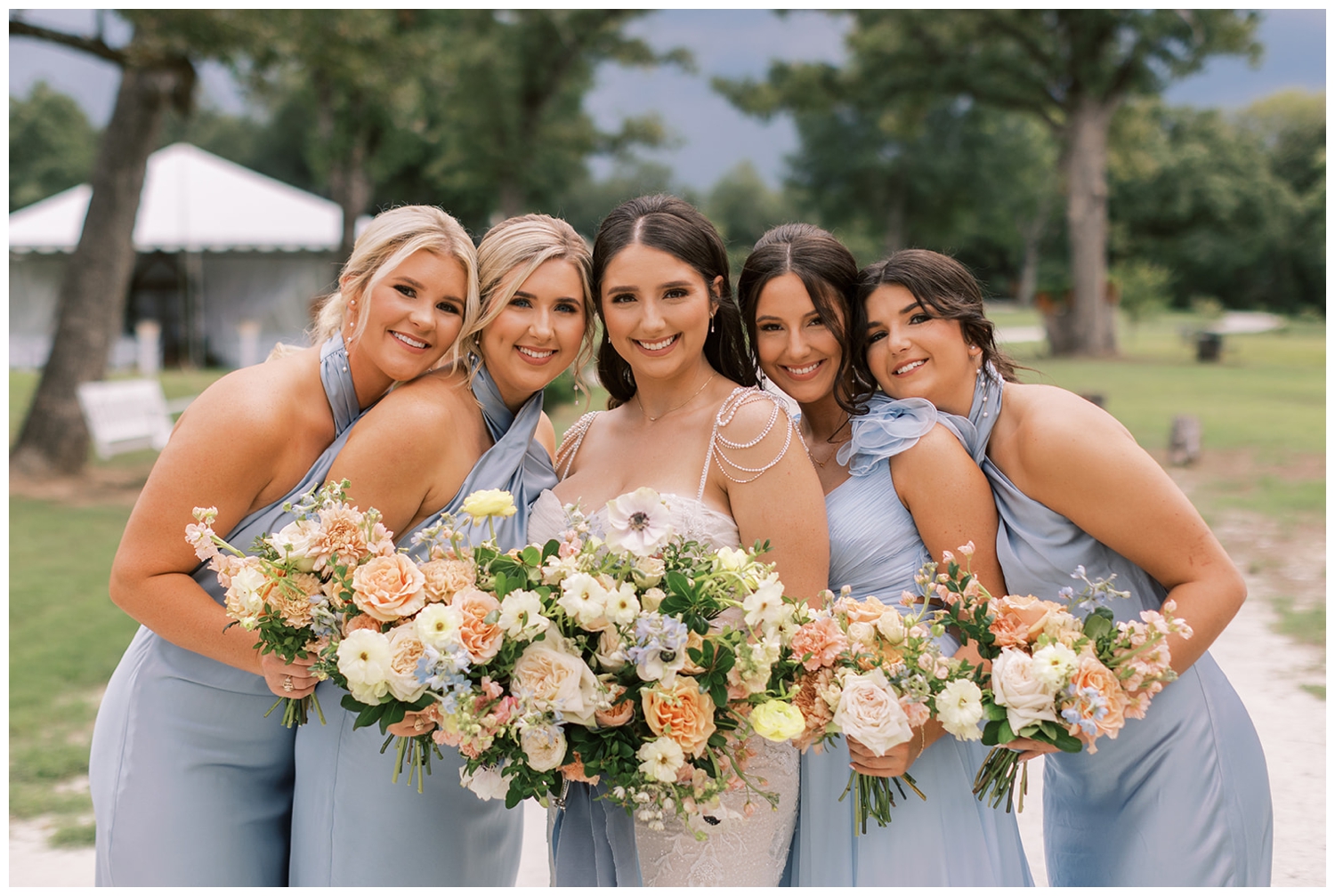 bride with bridesmaid in blue dresses standing outside Bluebird Haven Estates Wedding