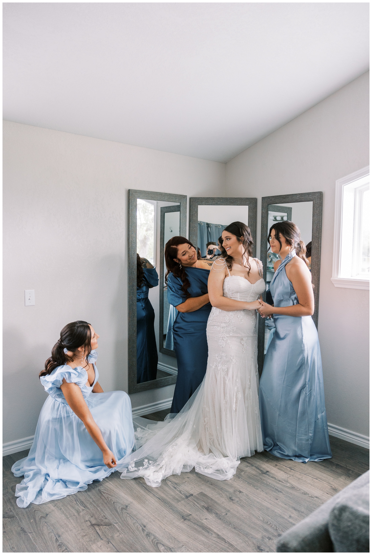 bride getting ready with mom and bridesmaids in blue dresses inside bridal suite at Bluebird Haven Estates wedding venue in Madisonville Texas