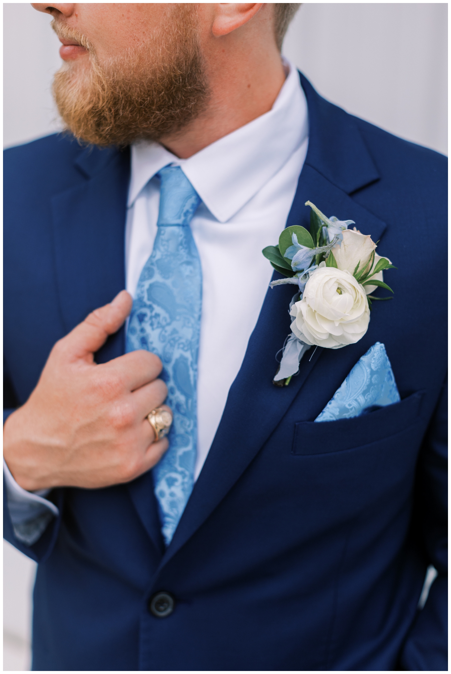 groom in blue suit with blue tie holding jacket