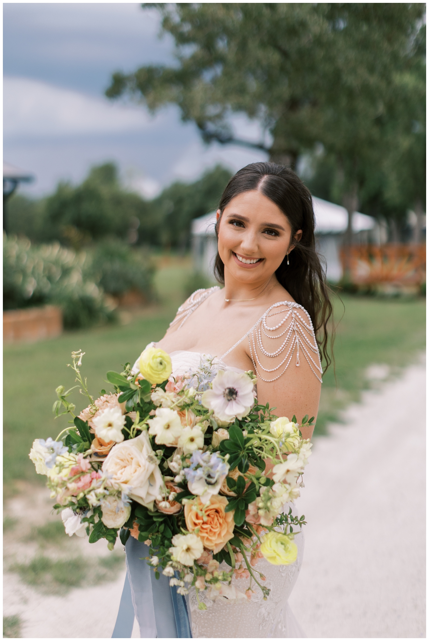 bride holding blue peach and white floral bouquet and smiling