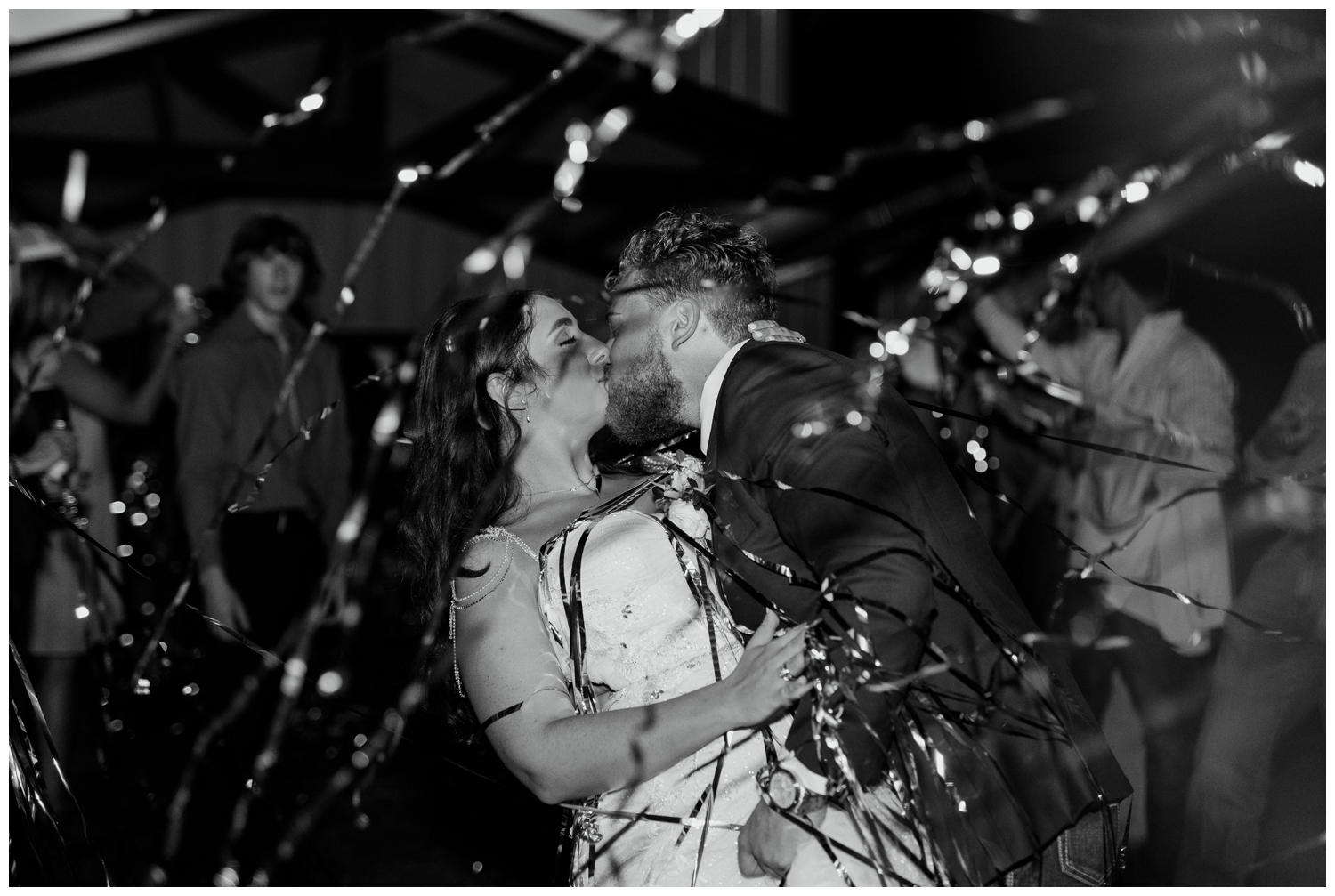 bride and groom kissing with streamers flying around them at Bluebird Haven Estates Wedding reception