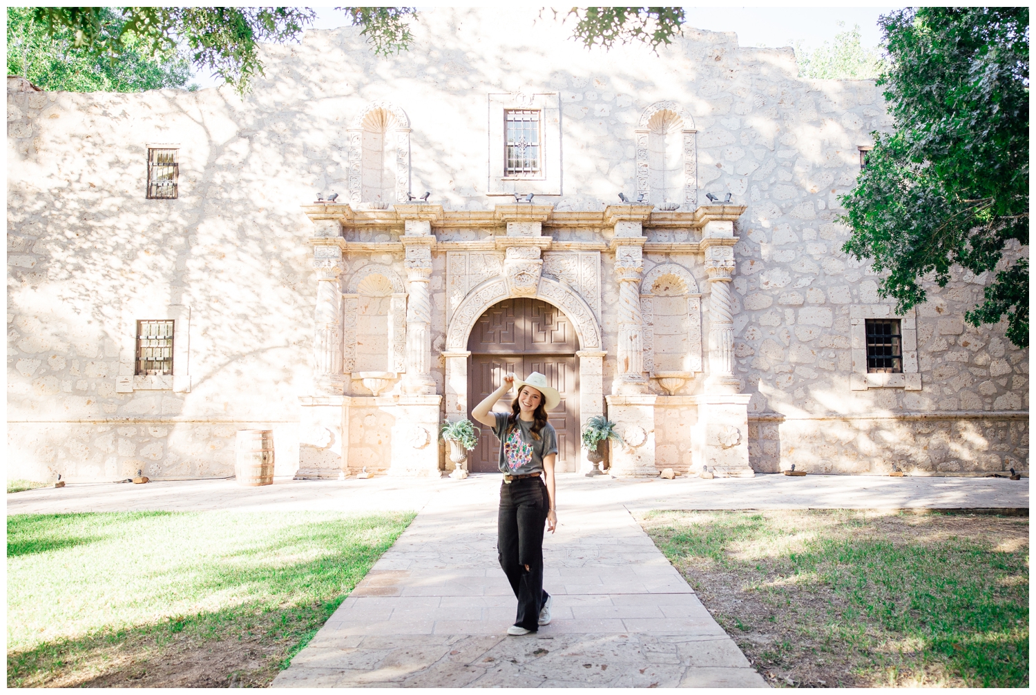 senior girl in black jeans, t-shirt and cowboy hat standing in front of Alamo building at Cy-Hope in Houston, Texas