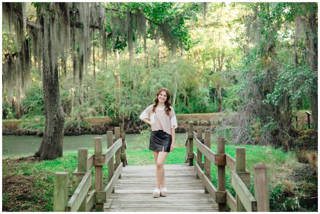 girl standing on a bridge in black skirt cream sweater at Cy-Hope fall senior photos Houston