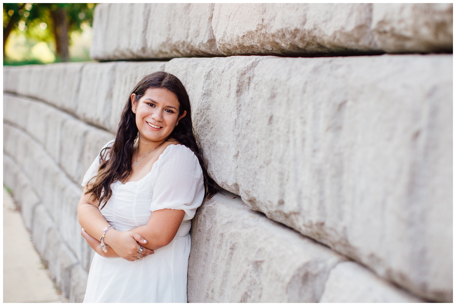 girl in white dress smiling with arms crossed outdoors for Senior Photos in Houston