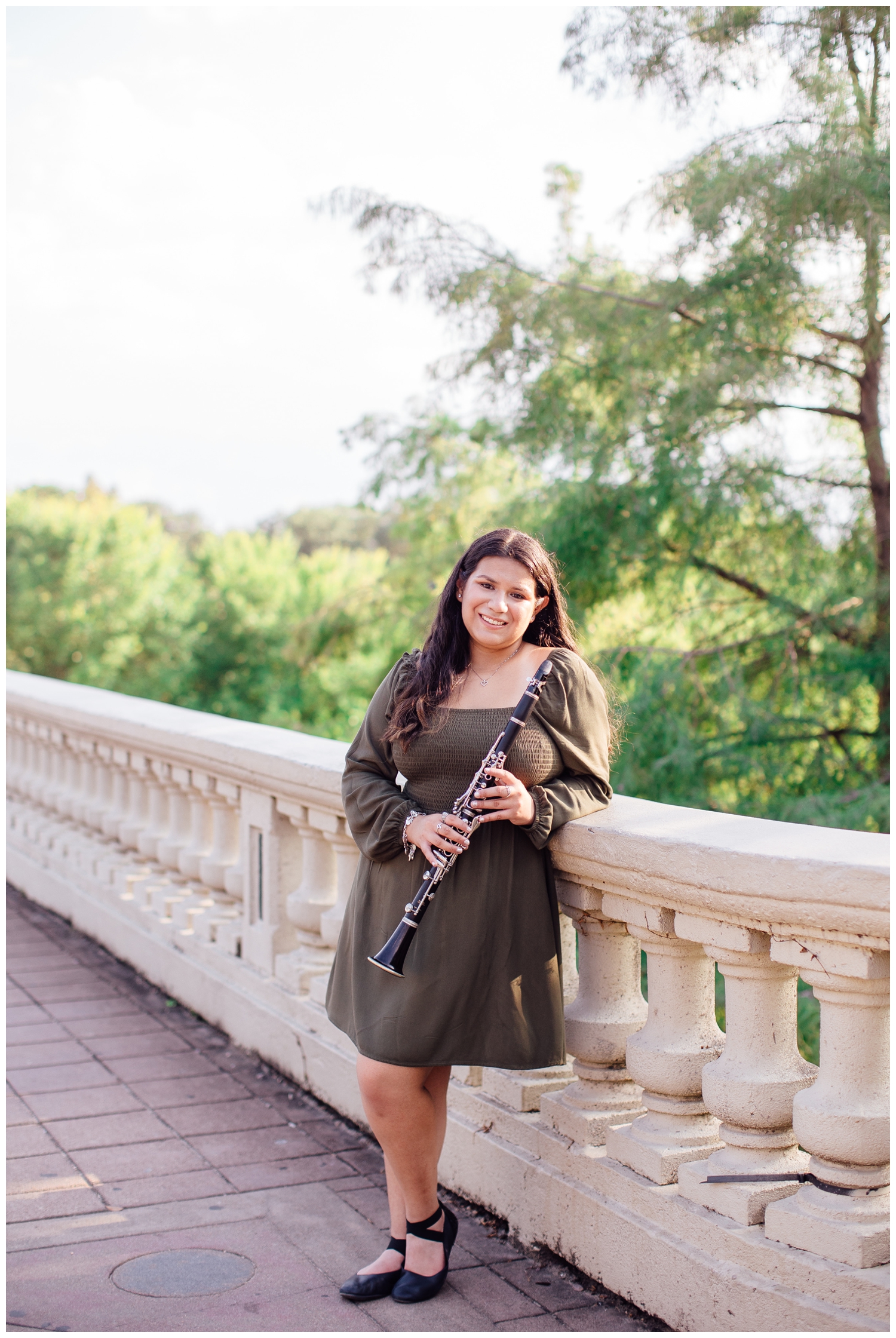 high school senior girl in green dress holding clarinet on Sabine Street Bridge
