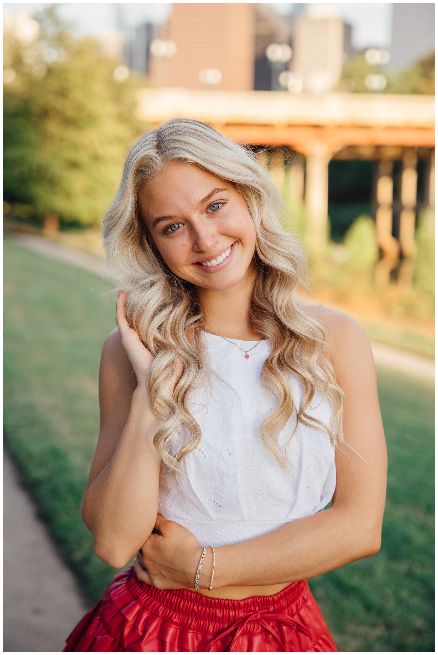 high school senior girl with white top smiling with hand in hair chic Houston senior pictures