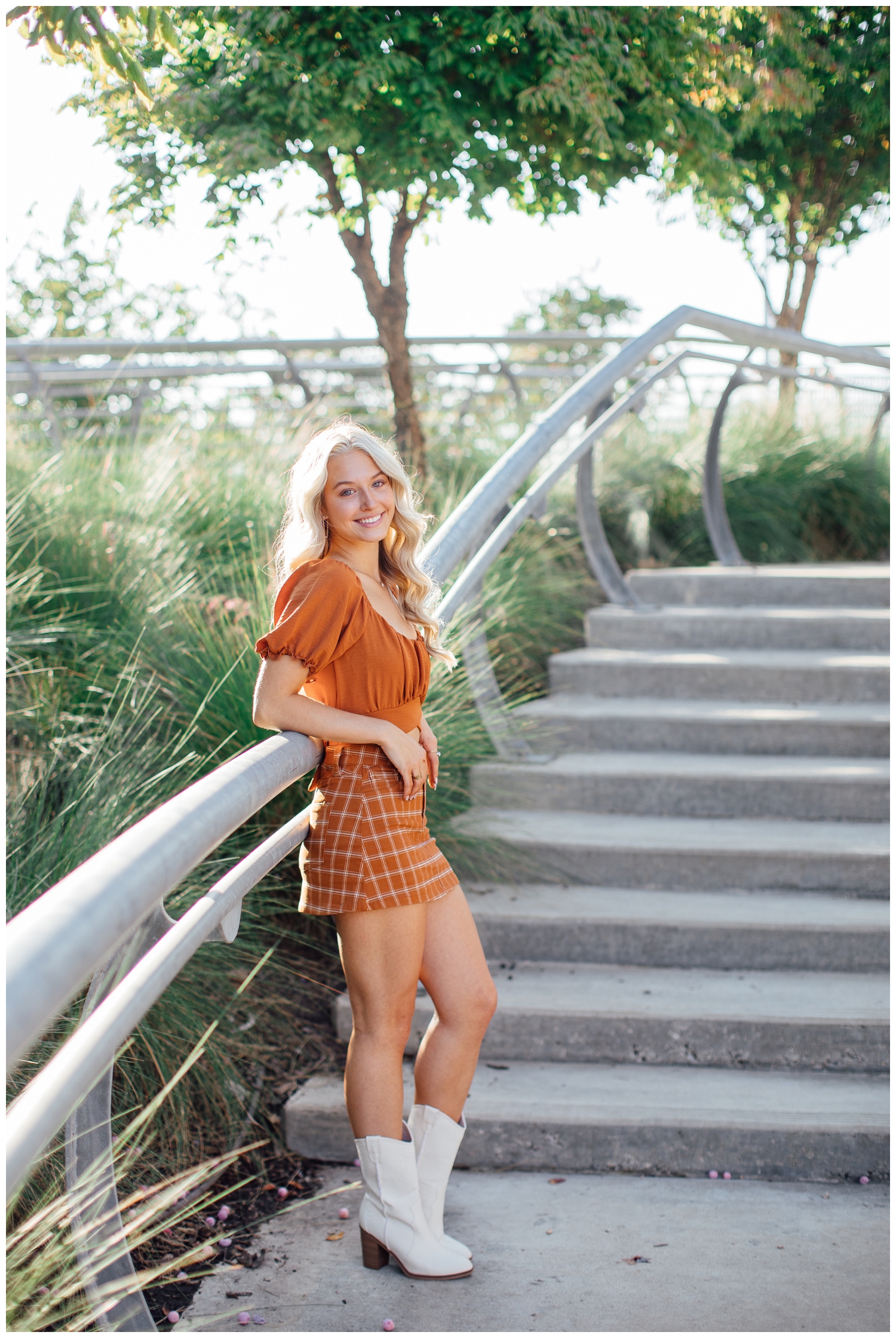 high school senior girl in rust plaid skirt and shirt leaning on rail at Sabine Street Houston