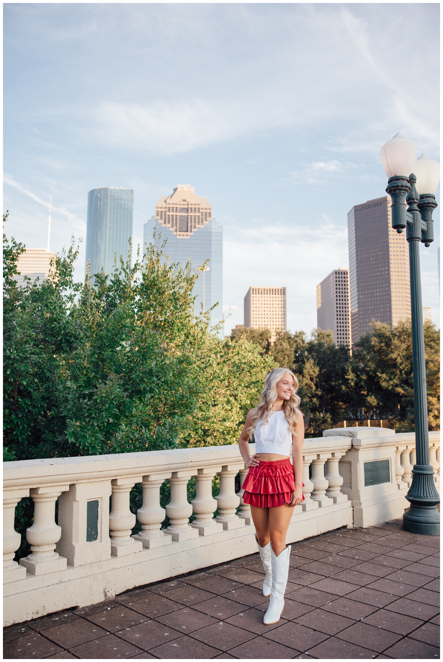 chic Houston senior pictures with girl in white shirt and short pink skirt standing on Sabine Street Bridge