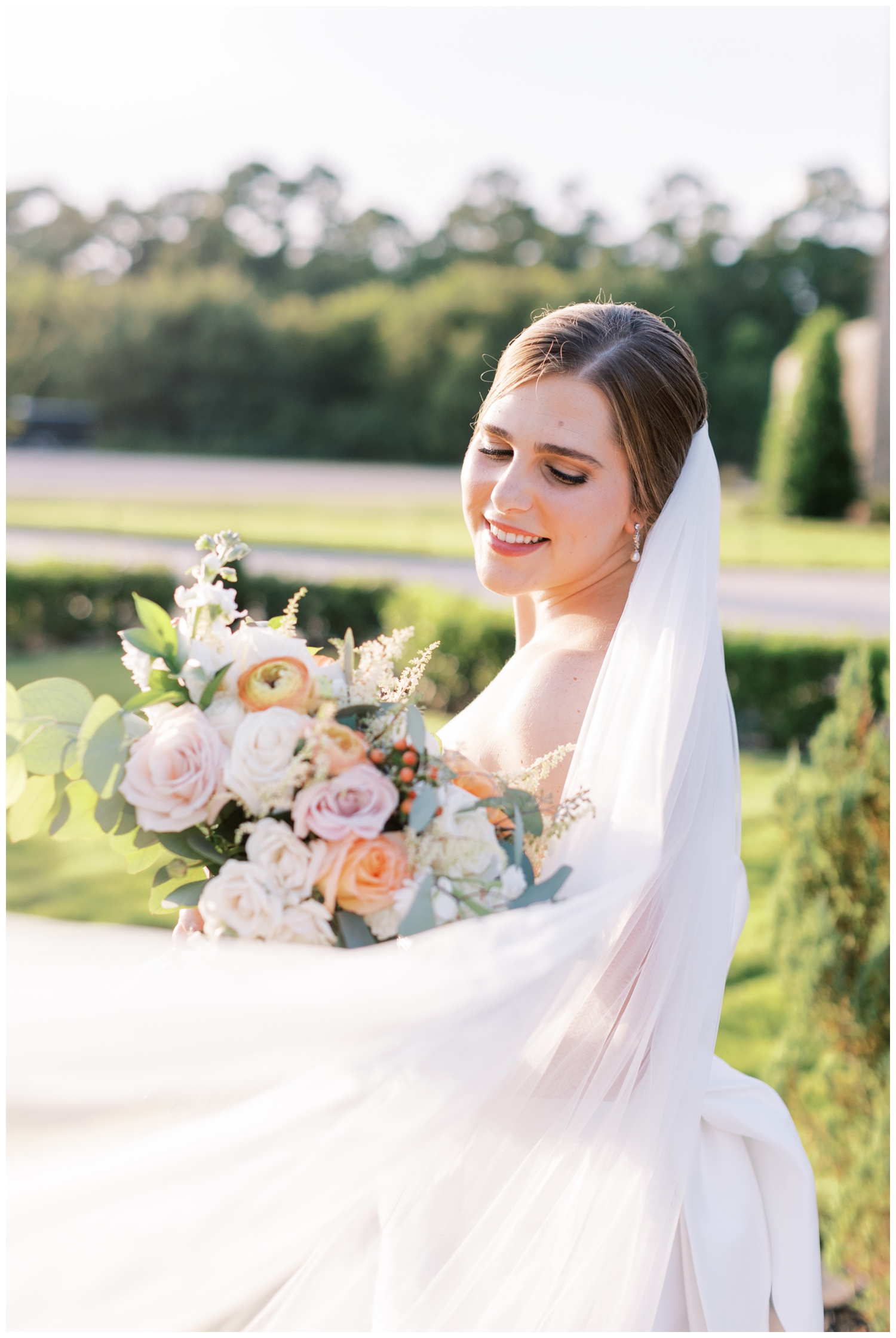 bride smiling at camera for portrait with veil swoop outside elegant Iron Manor wedding venue