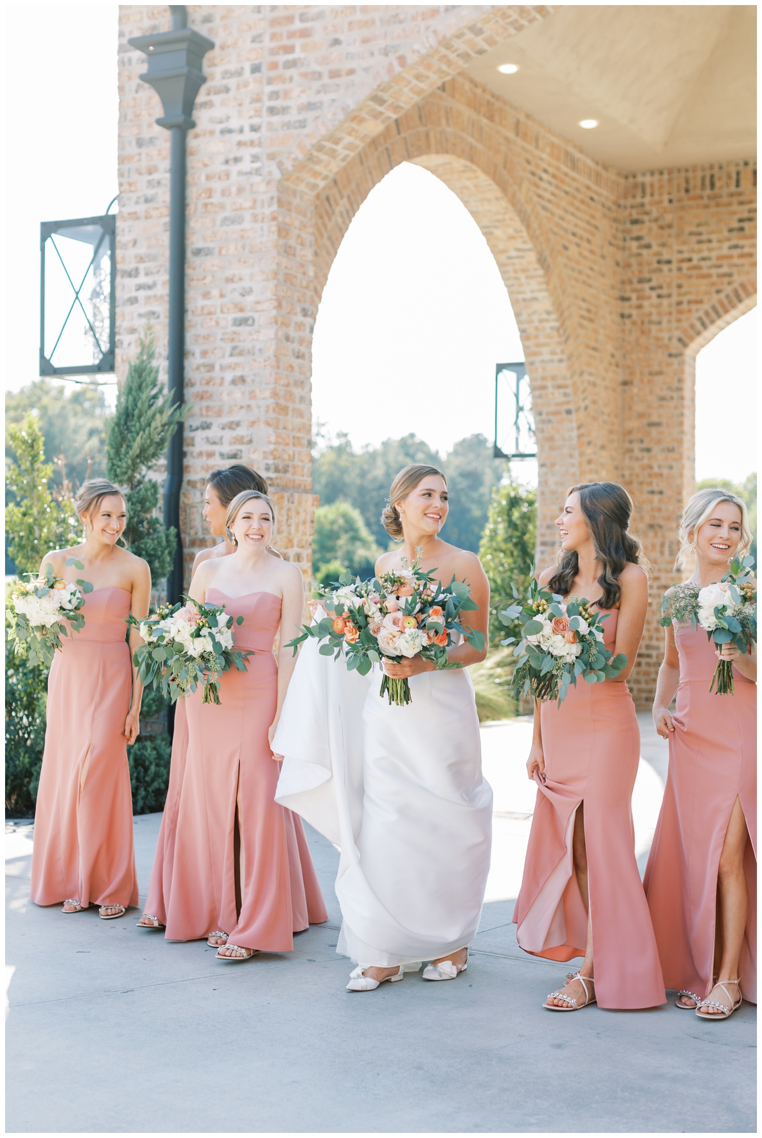 bride laughing and walking with bridesmaids in blush dressed outside elegant Iron Manor Wedding