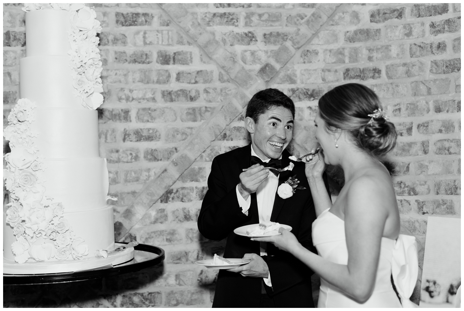black and white image of bride and groom eating their cake