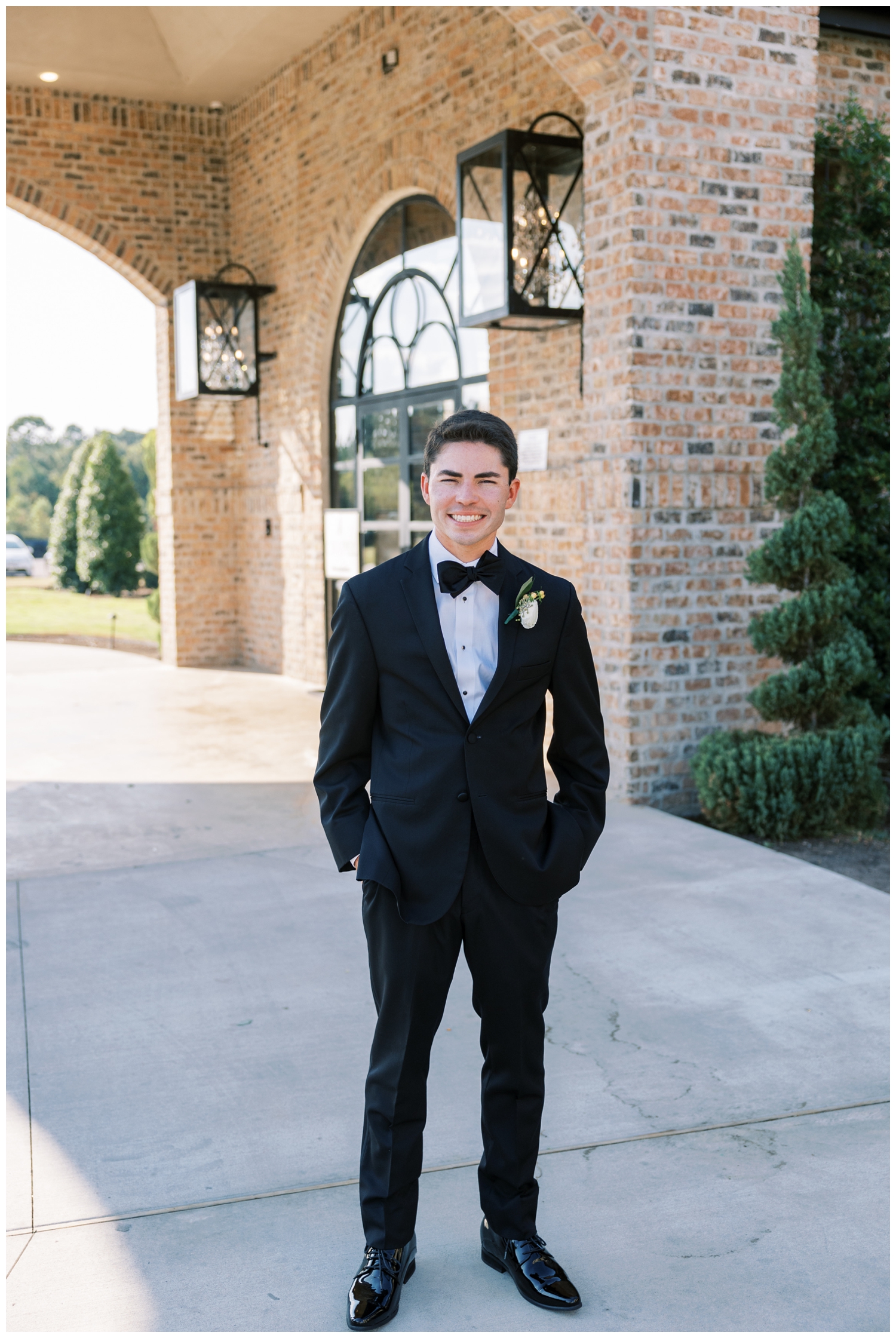 groom in black tux standing outside Iron Manor Wedding in Conroe, Texas