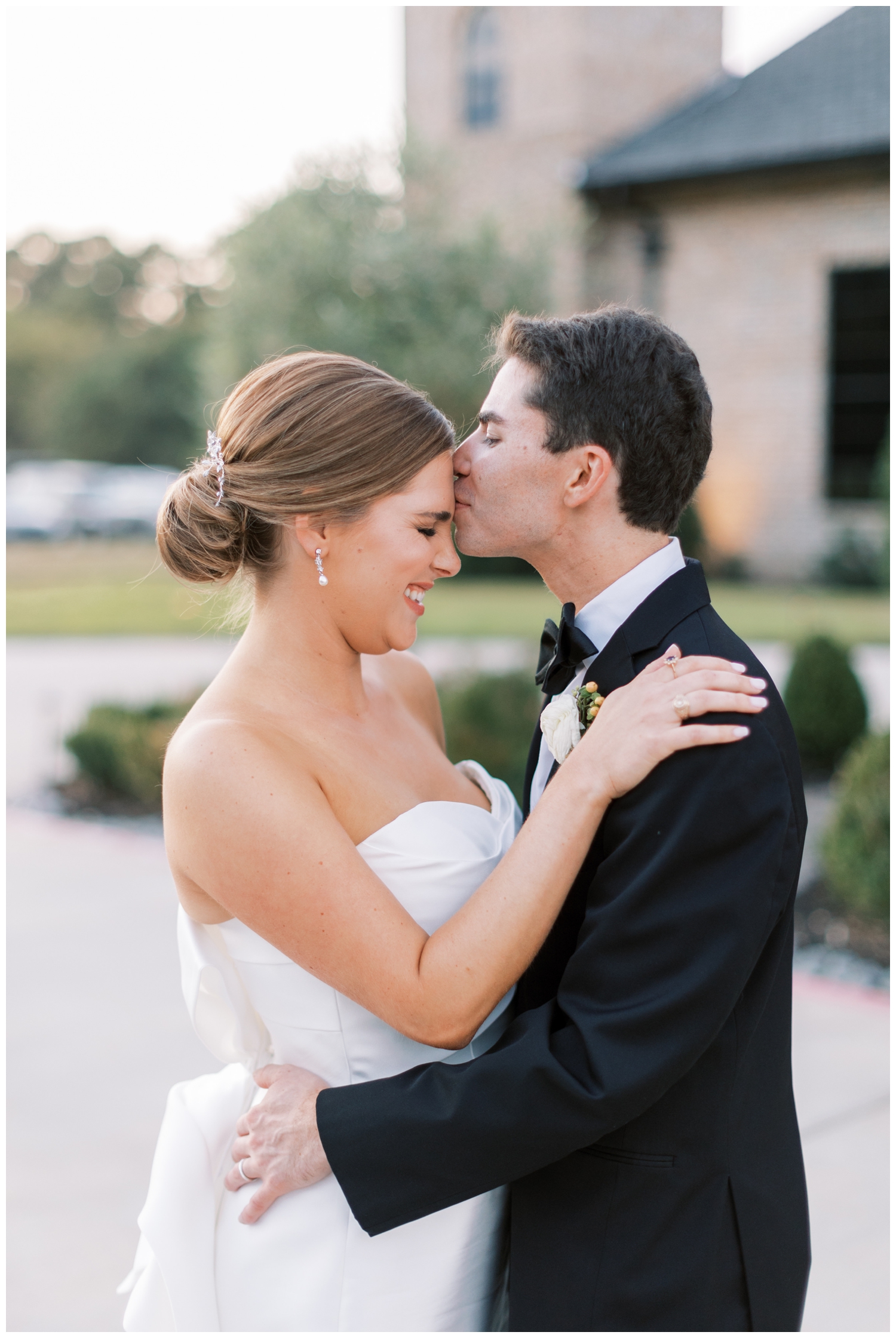groom kissing bride's forehead for outdoor Iron Manor portrait