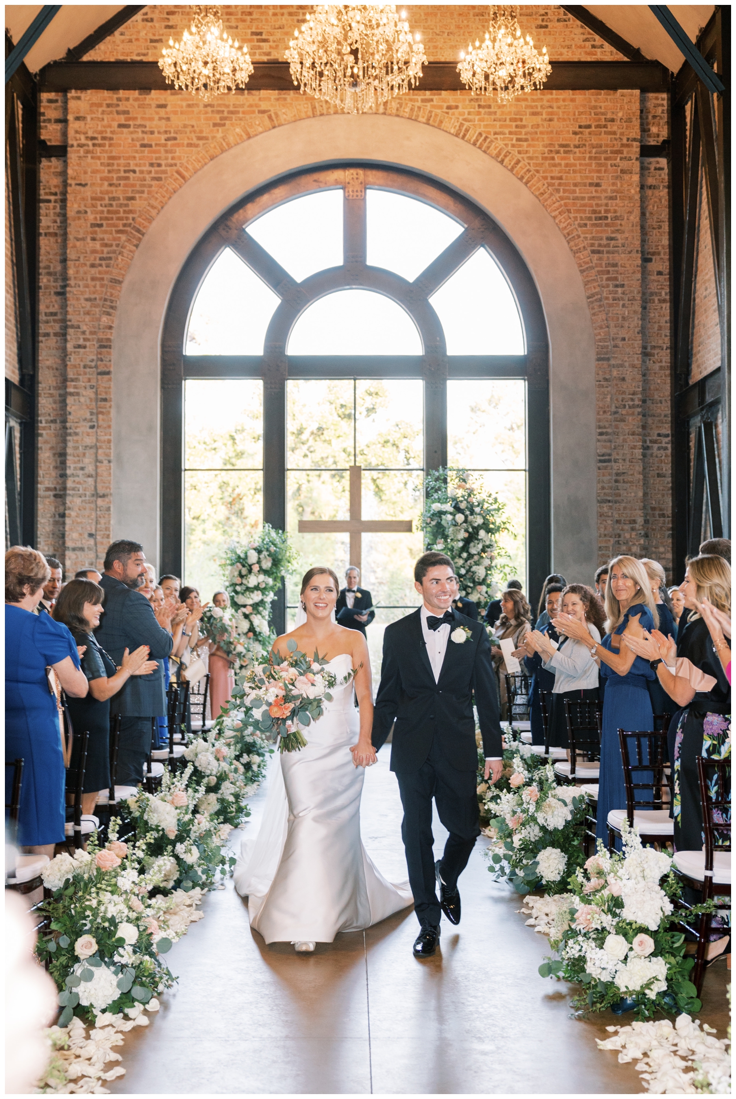 bride and groom holding hands and walking up ceremony aisle inside Iron Manor