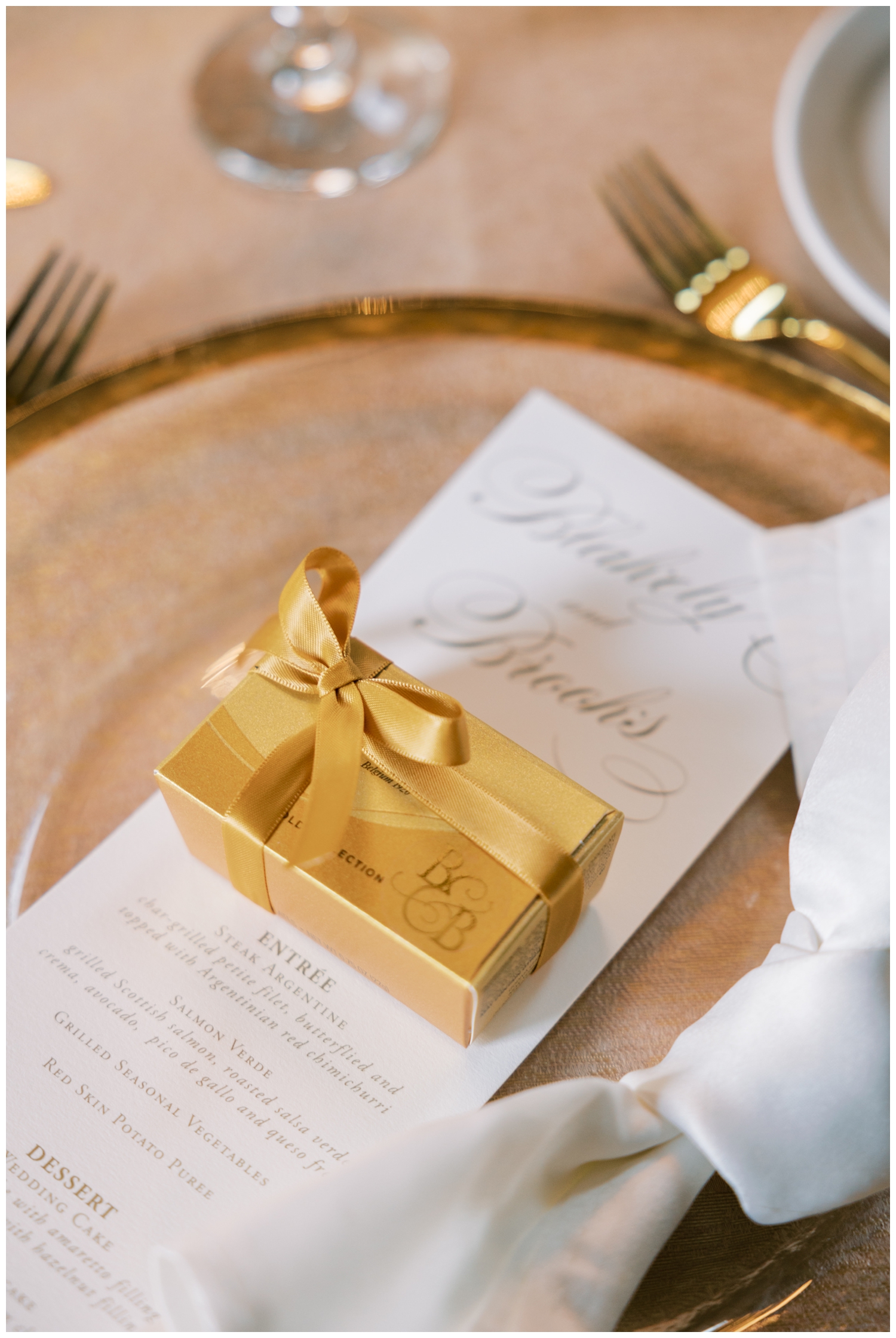 detailed image of gold Godiva box on white invitation and gold place setting