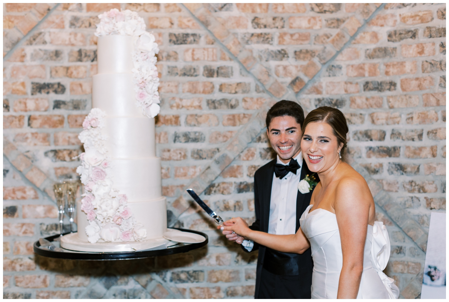 bride and groom smiling and cutting white wedding cake