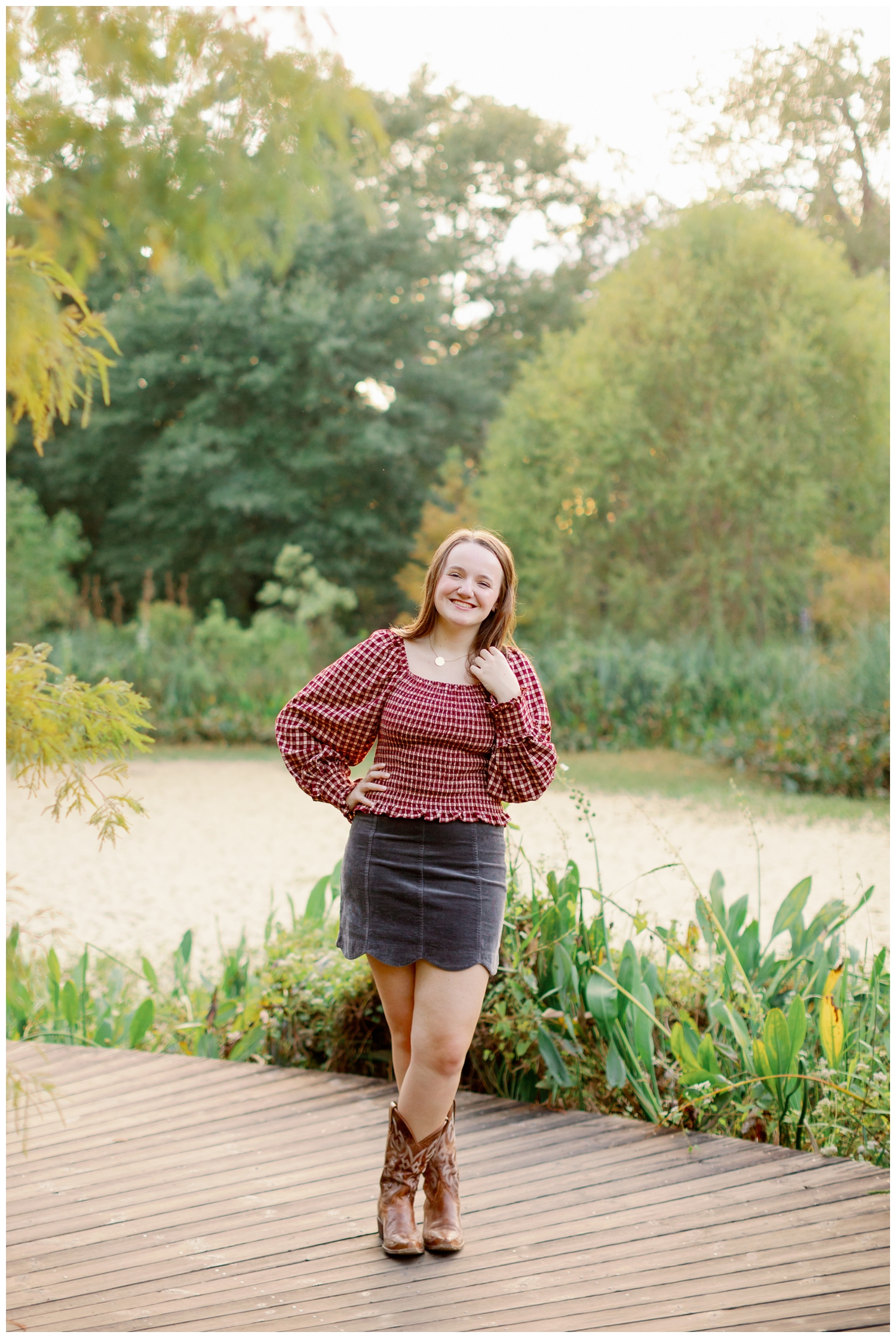 high school senior in black skirt and maroon shirt with hand in hair