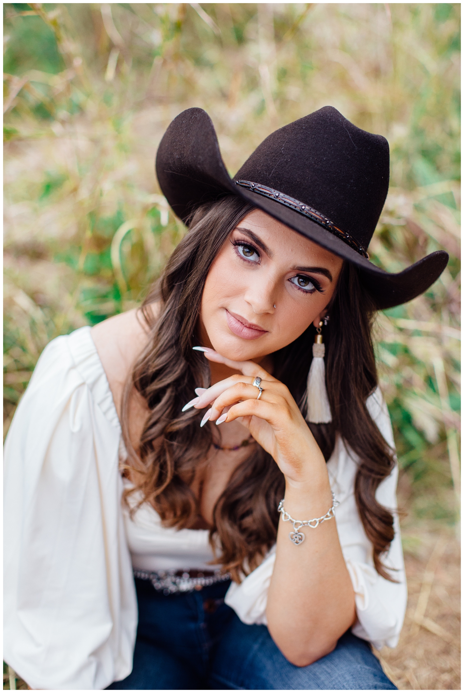 closeup portrait of girl with finger on chin wearing black cowboy hat for bold senior portraits in Houston