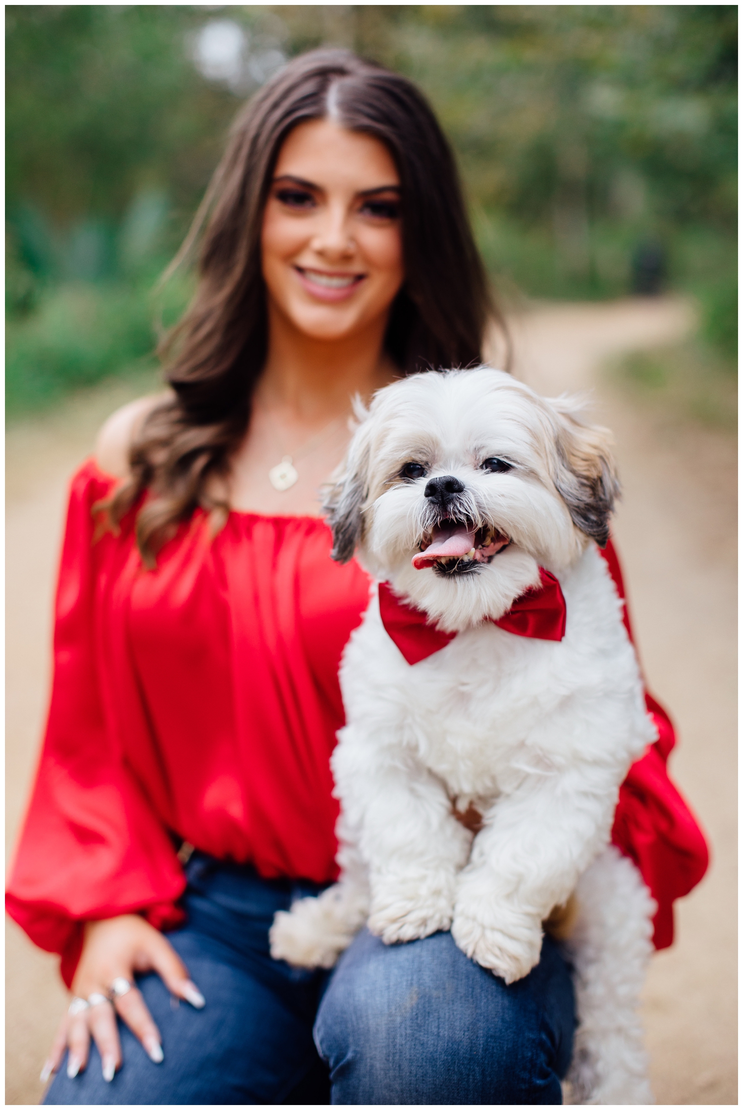 high school senior girl holding white dog wearing red bow tie
