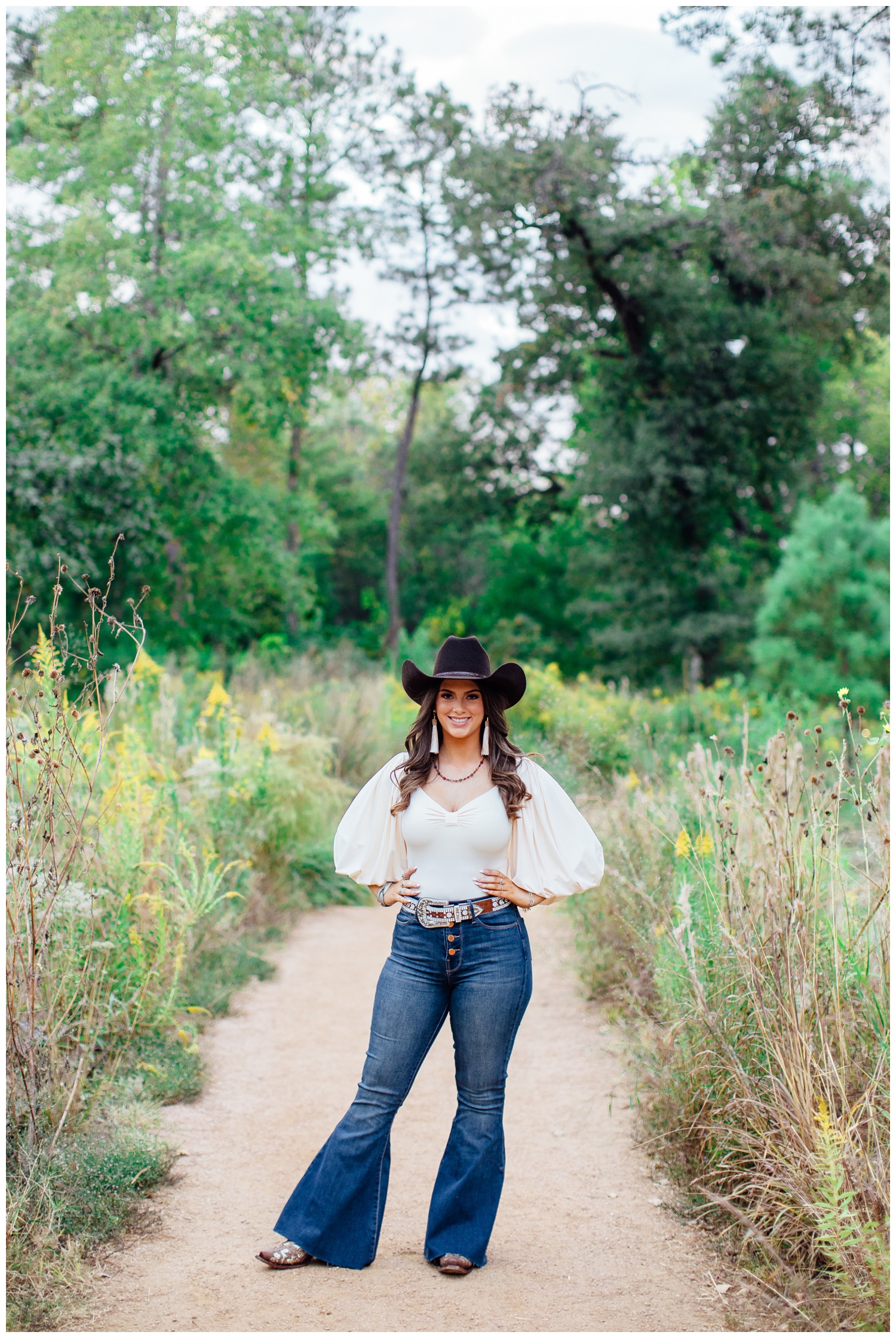 Houston senior girl standing in jeans with cowboy hat standing on pathway hands on hip