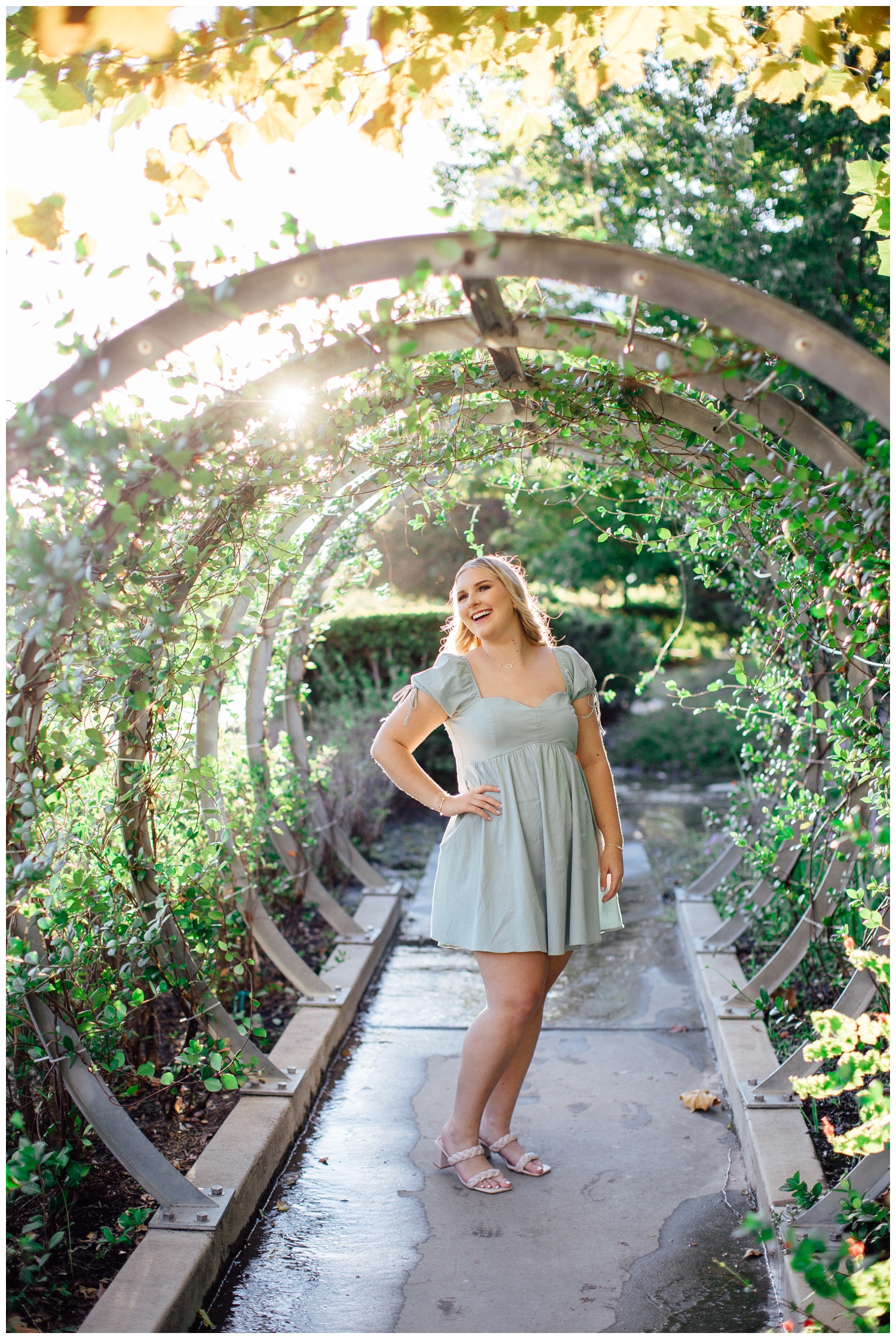 high school senior girl in dress standing under floral arch for cute senior pictures in Houston downtown