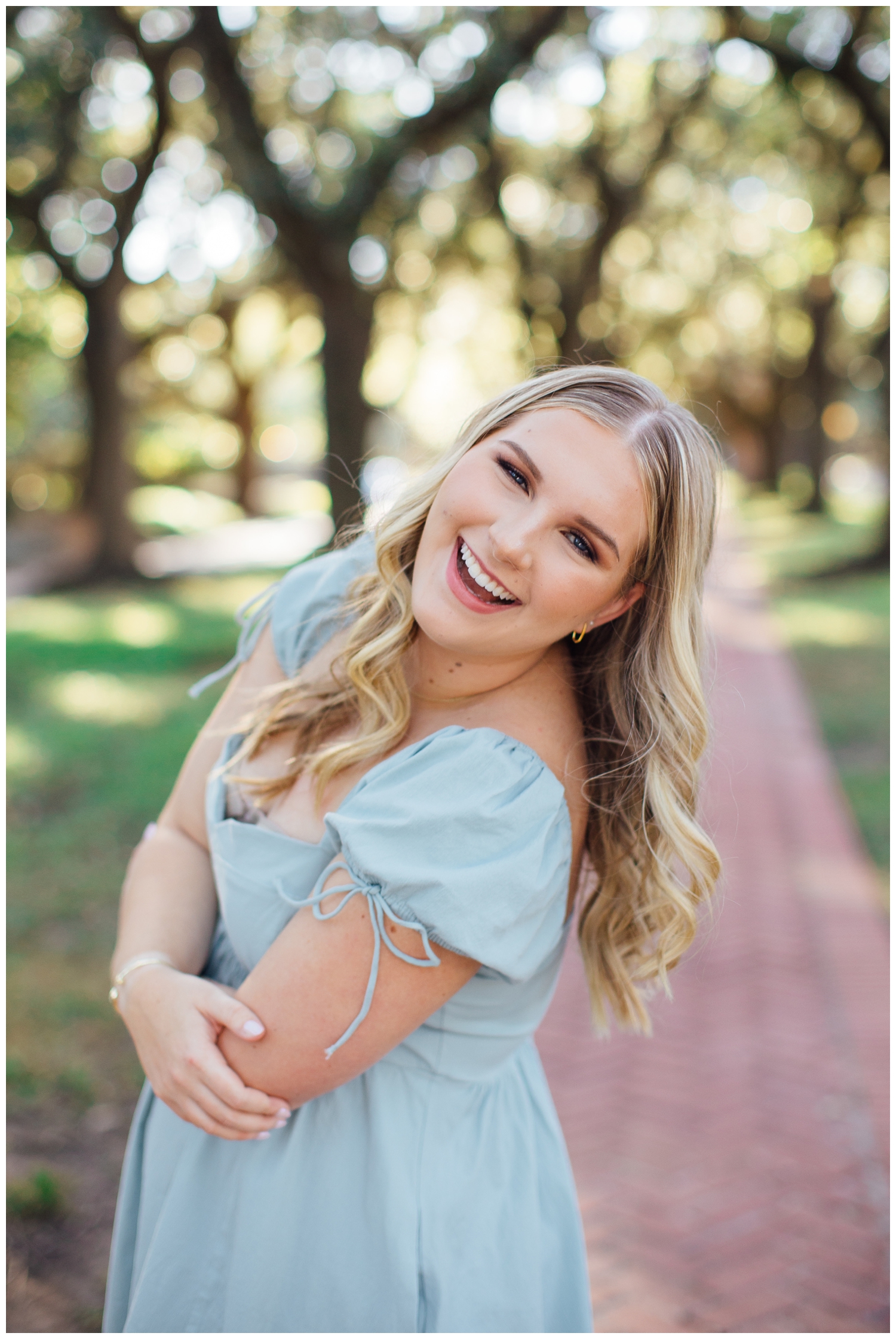 high school senior girl leaning toward camera smiling outdoors Houston North South Boulevard