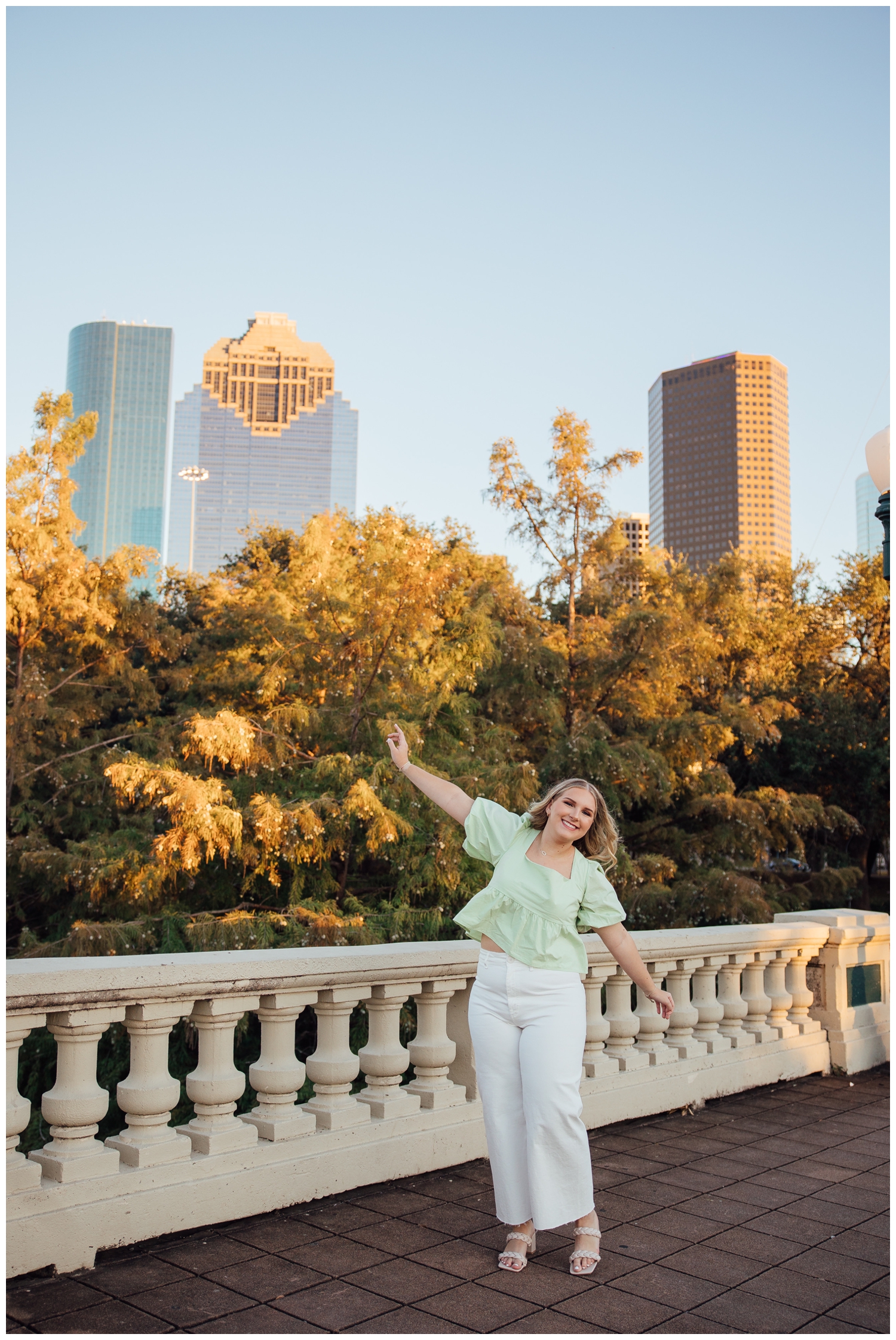 girl with hands in air standing in front of downtown Houston skyline