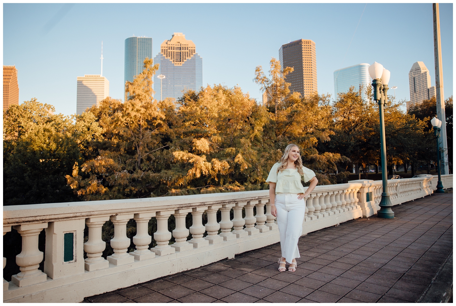 high school senior girl walking on Sabine Street Bridge with hand on hip and in front of Houston skyline