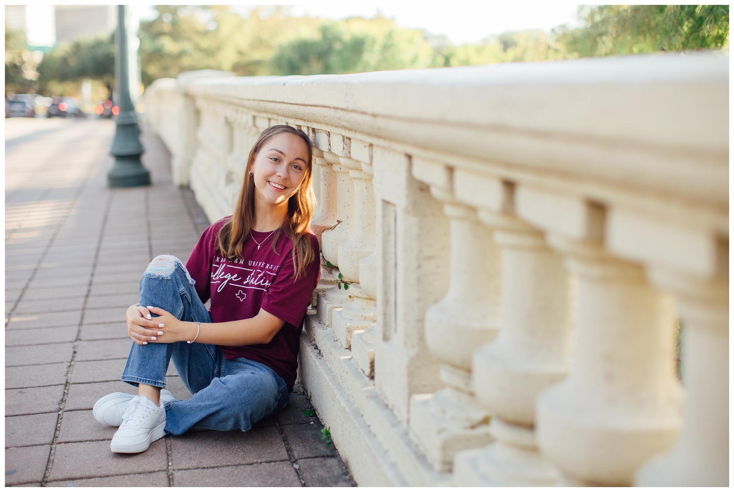 girl in maroon shirt and jeans sitting on Sabine Street Bridge downtown Houston