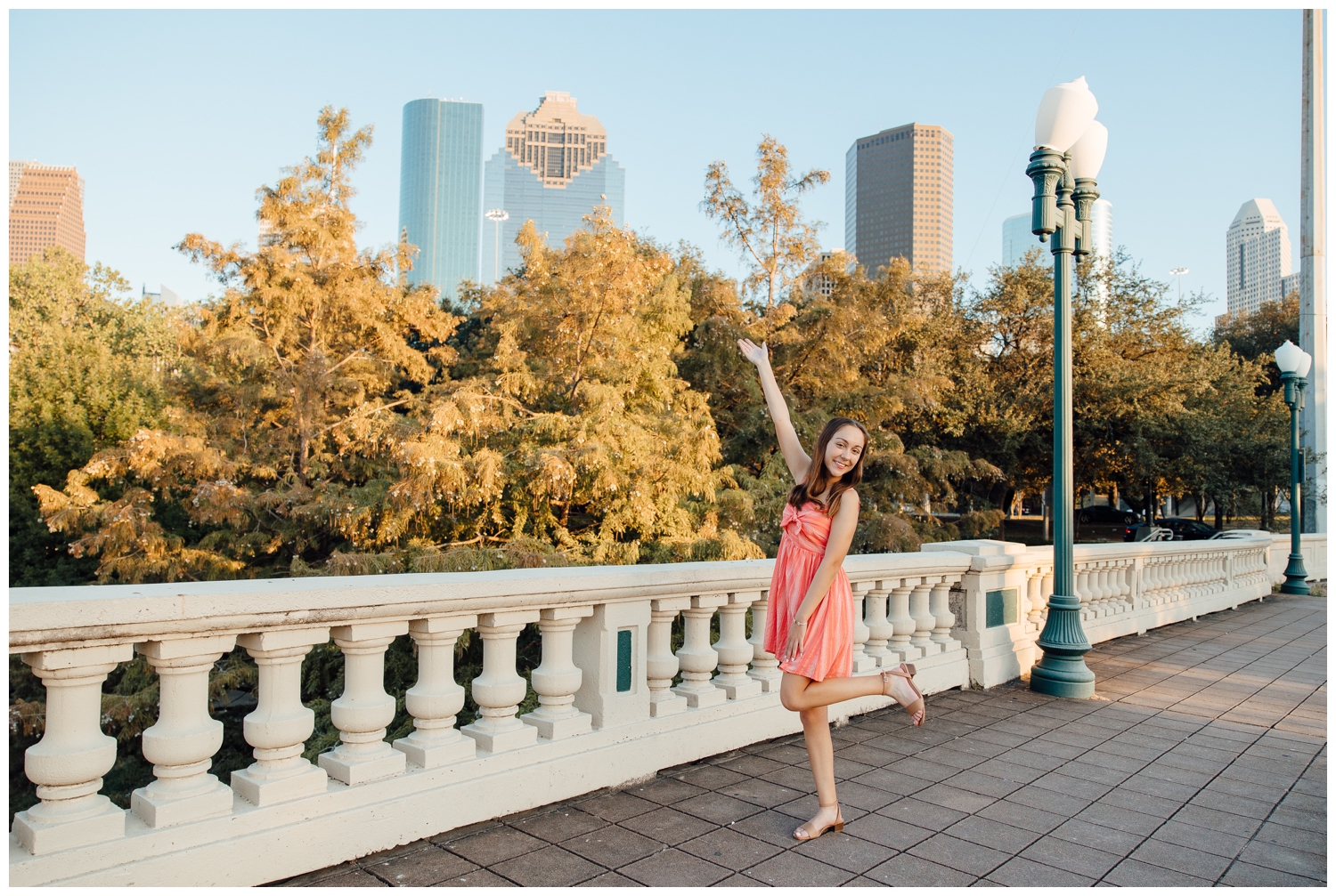 skyline downtown Houston senior picture with girl in coral dress on sabine bridge