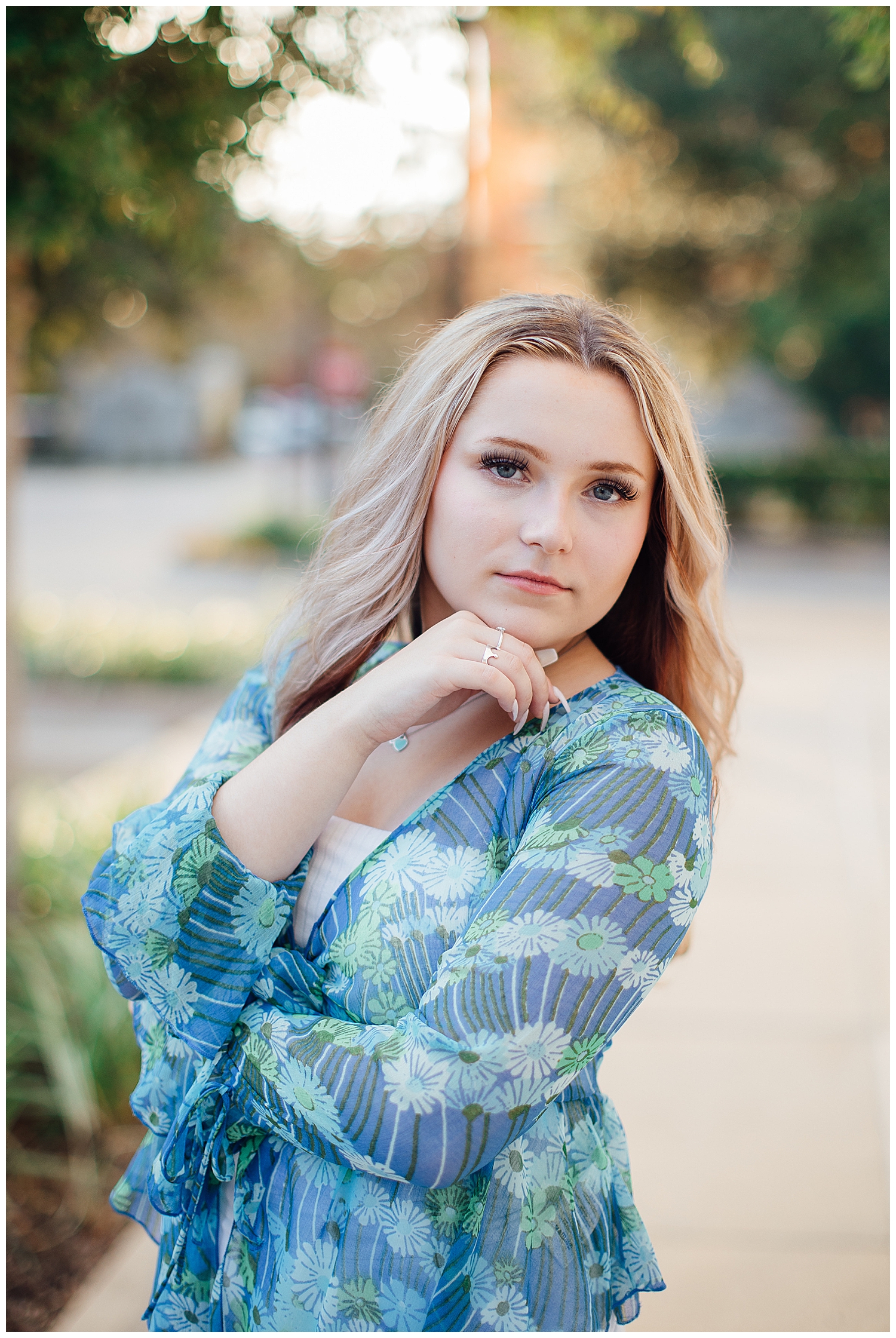 modern Houston senior girl with hand under chin looking at camera outdoors in blue blouse