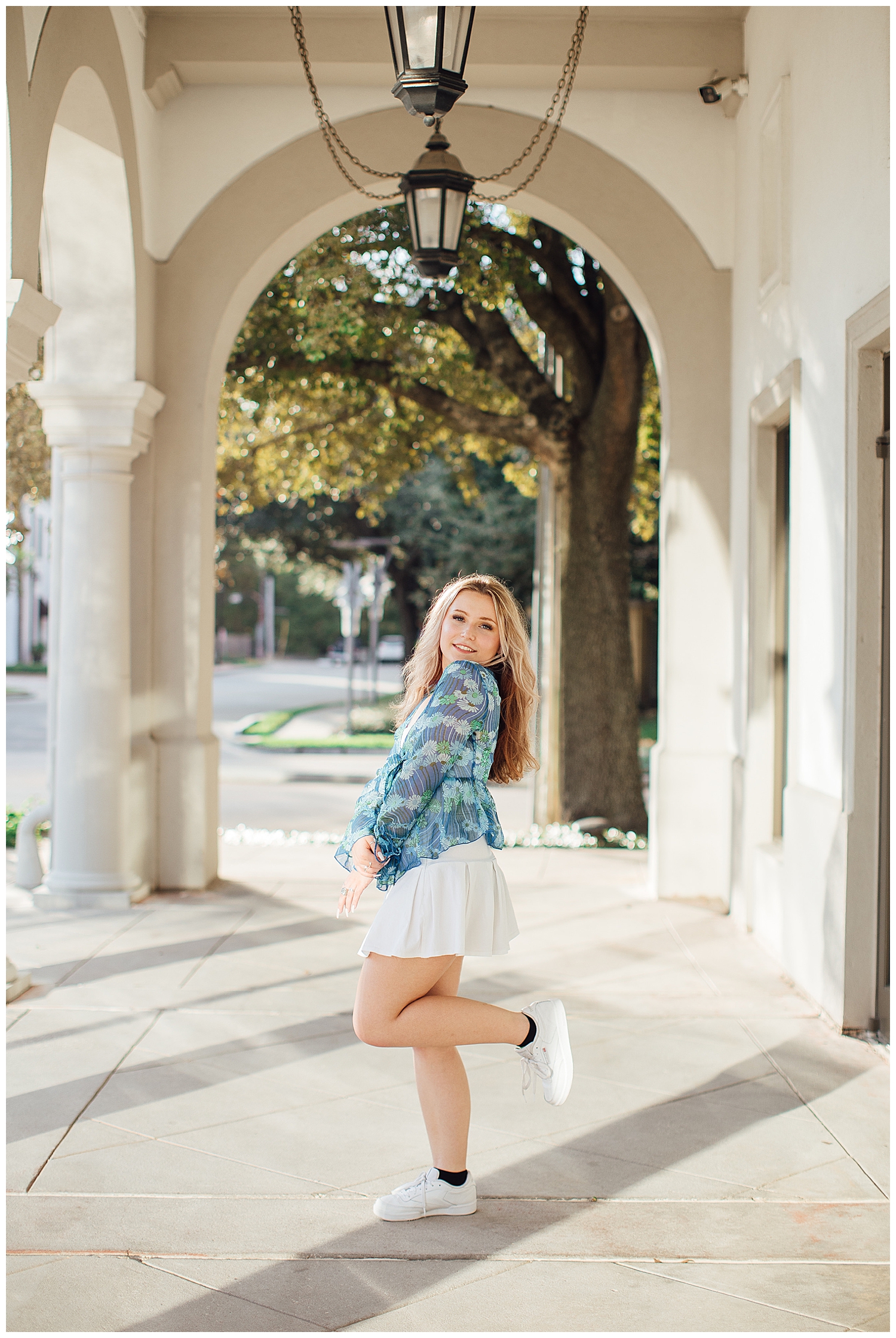 girl kicking heel in white skirt and blue blouse Uptown Park modern Houston senior photographer