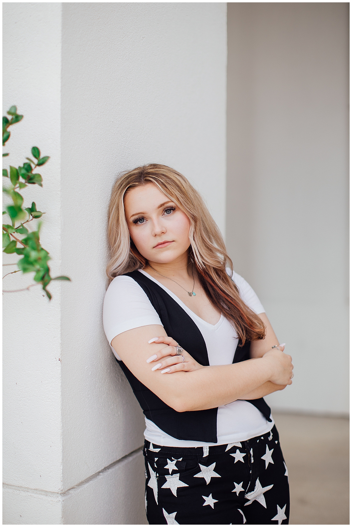 girl leaning on white building in Houston wearing white shirt black vest