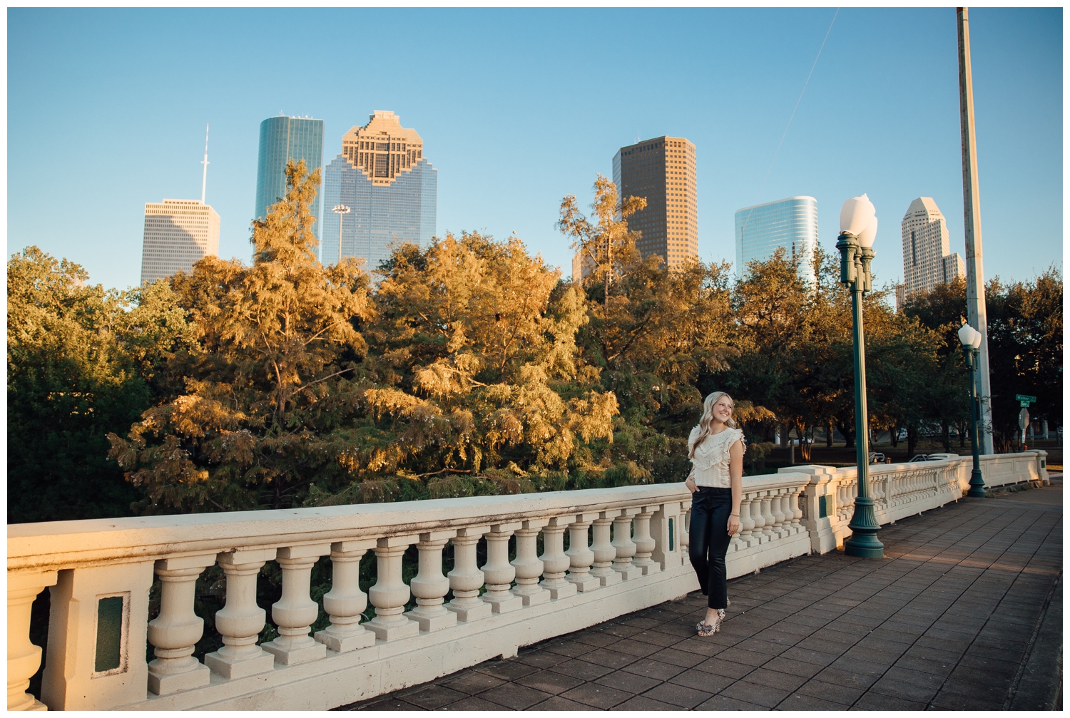 girl standing on Sabine Street bridge in front of Houston Skyline