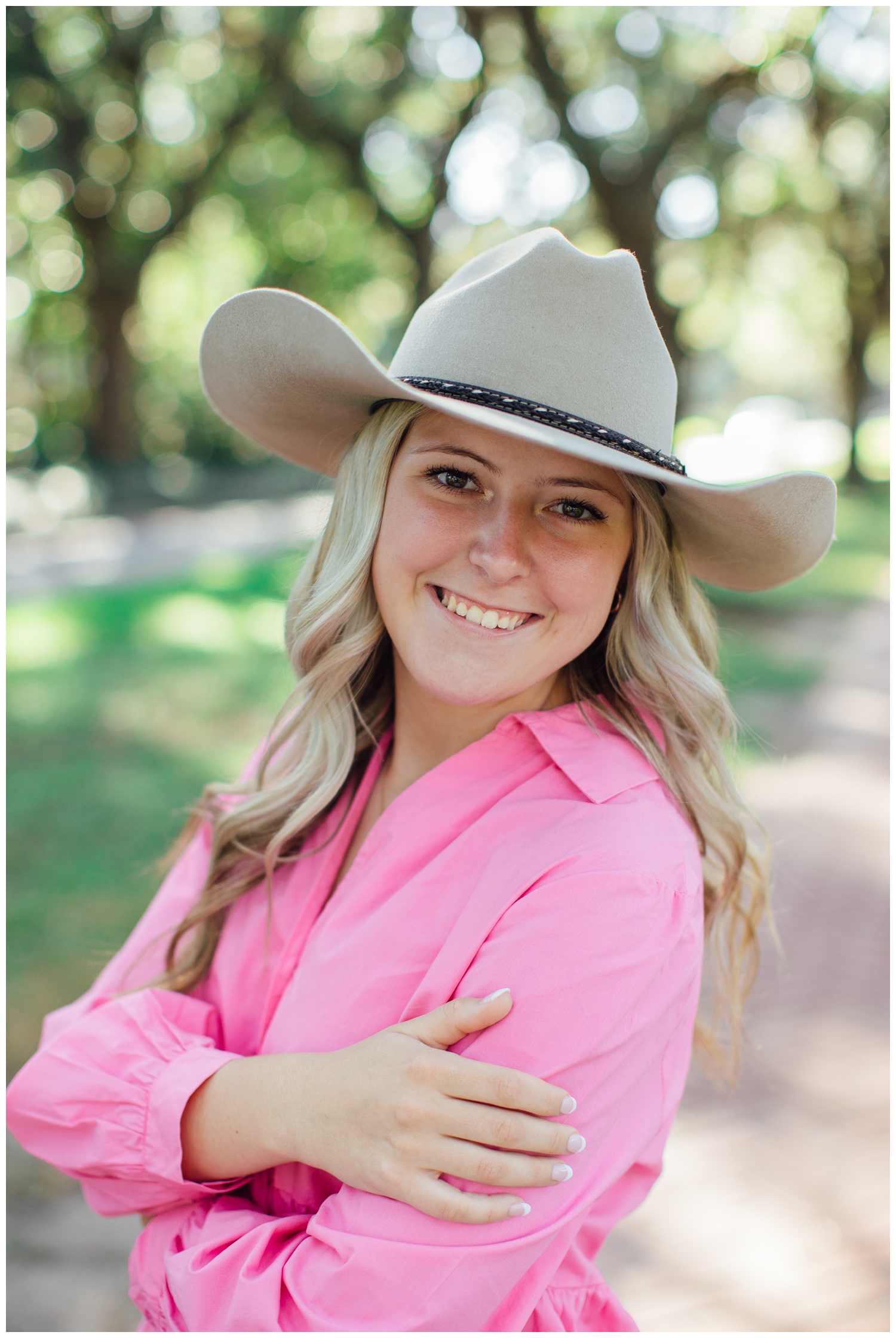 girl in cowboy hat and pink dress staring and smiling at camera