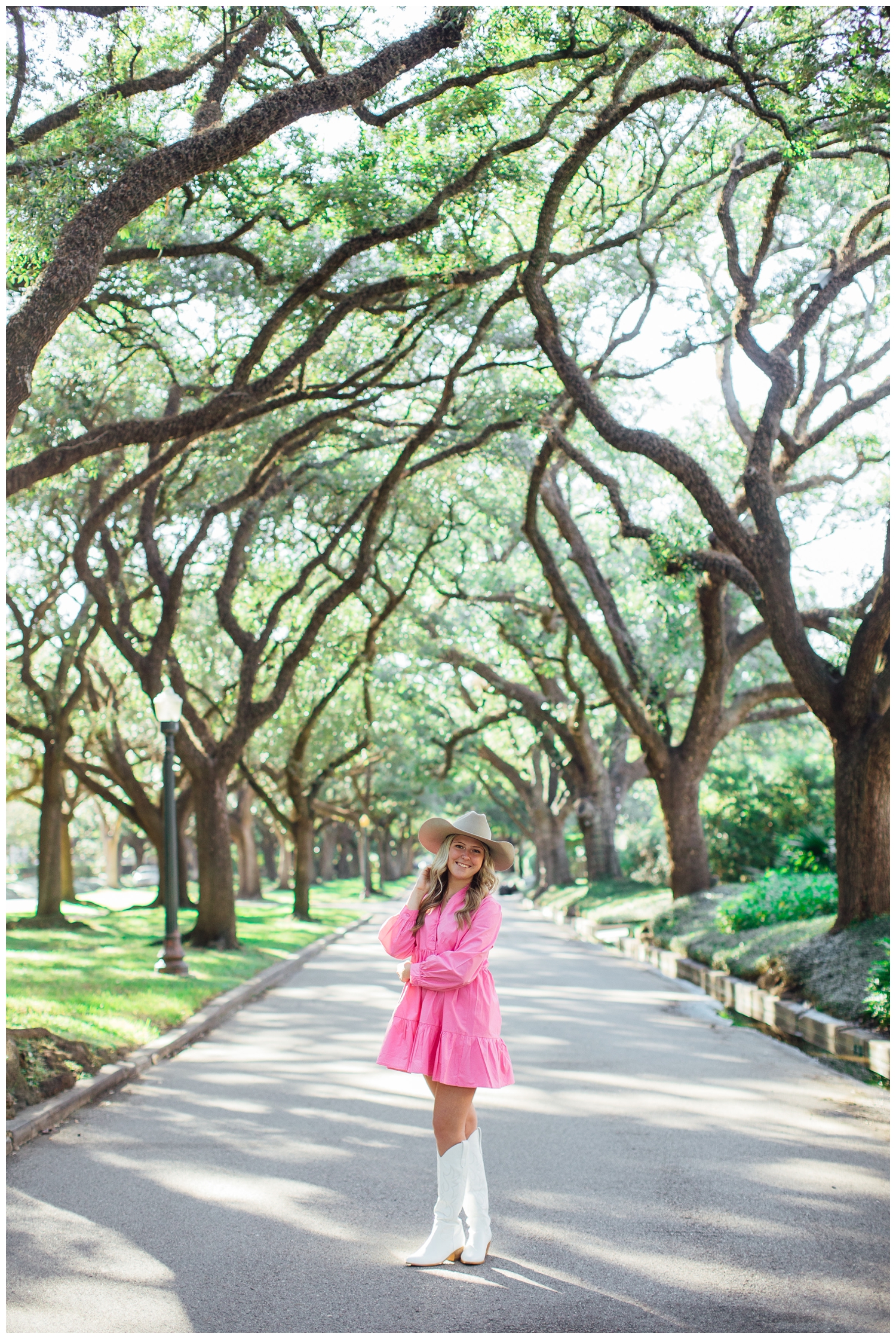 high school girl in pink dress, cowboy hat, white boots standing tree line