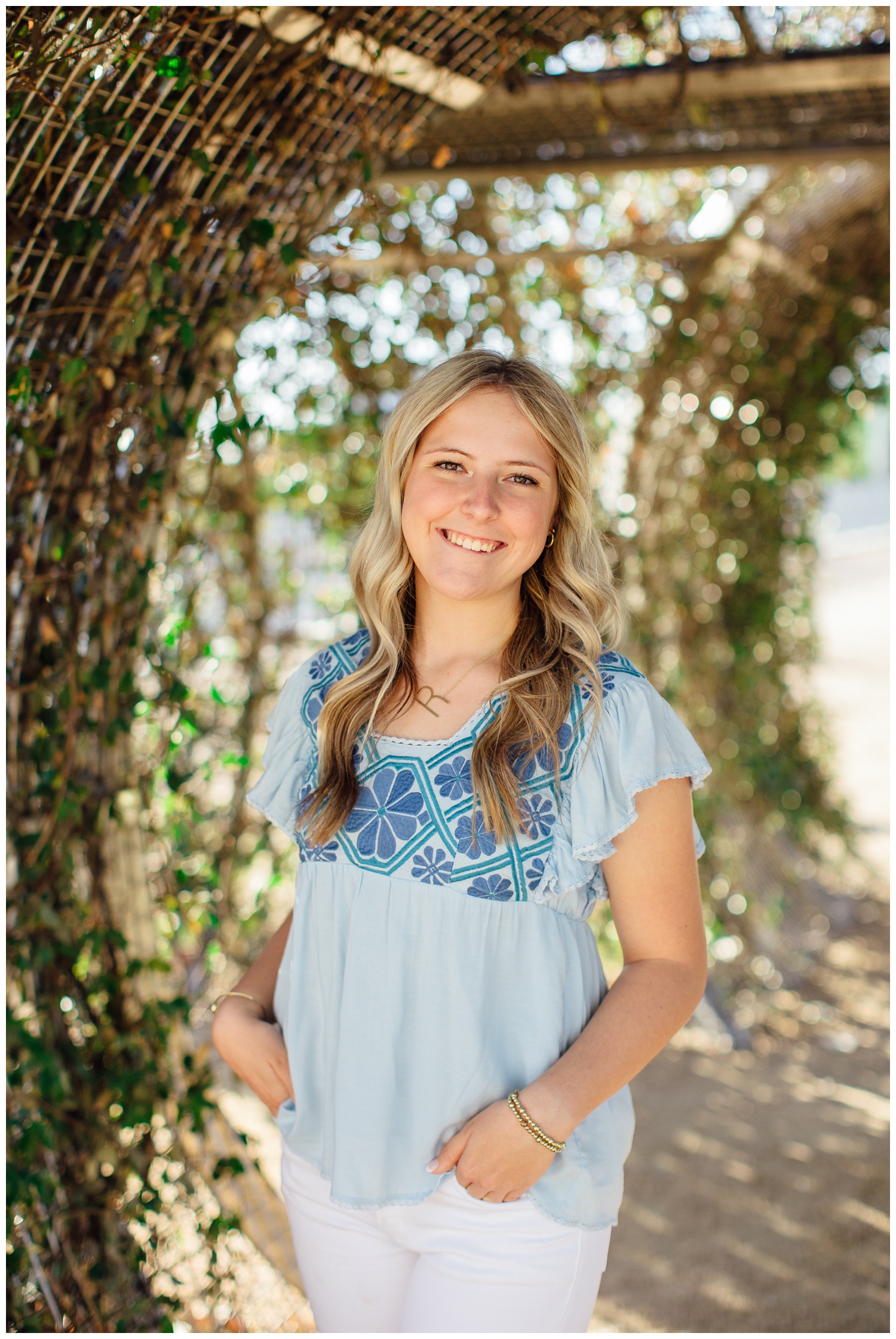 high school senior girl in light blue blouse standing in garden arch for Outdoor Houston senior photography