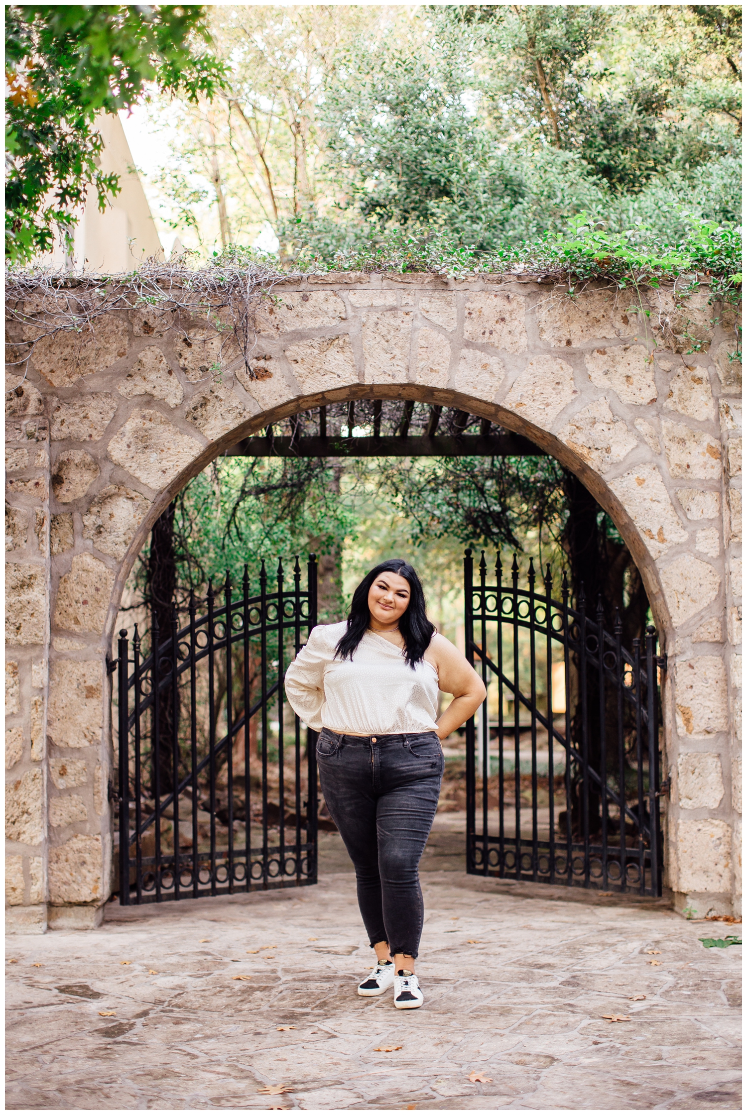 high school senior girl in black jeans and cream shirt standing with hands on hip Cypress Texas outdoors