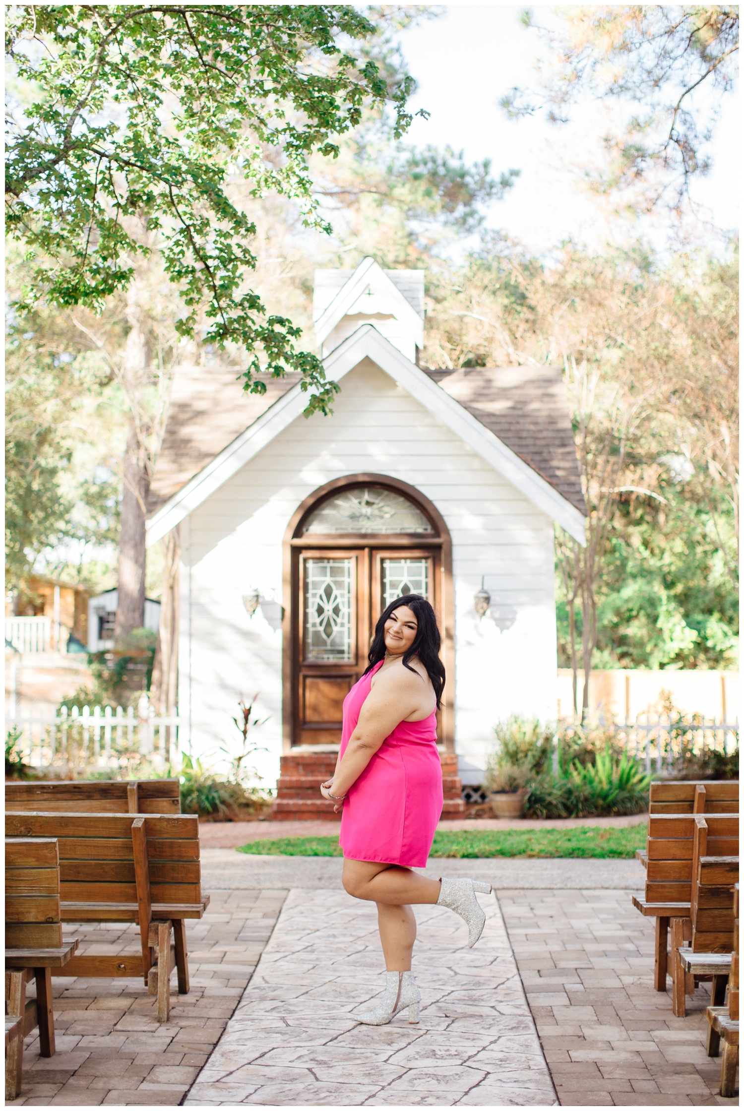 senior photographer in Cypress at Cy Hope with girl in hot pink dress smiling in front of white chapel