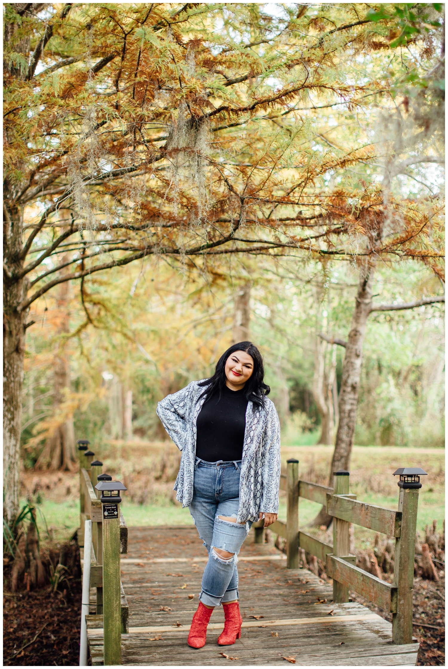 girl in denim and black standing on bridge at Cy Hope for for senior photographer in Cypress