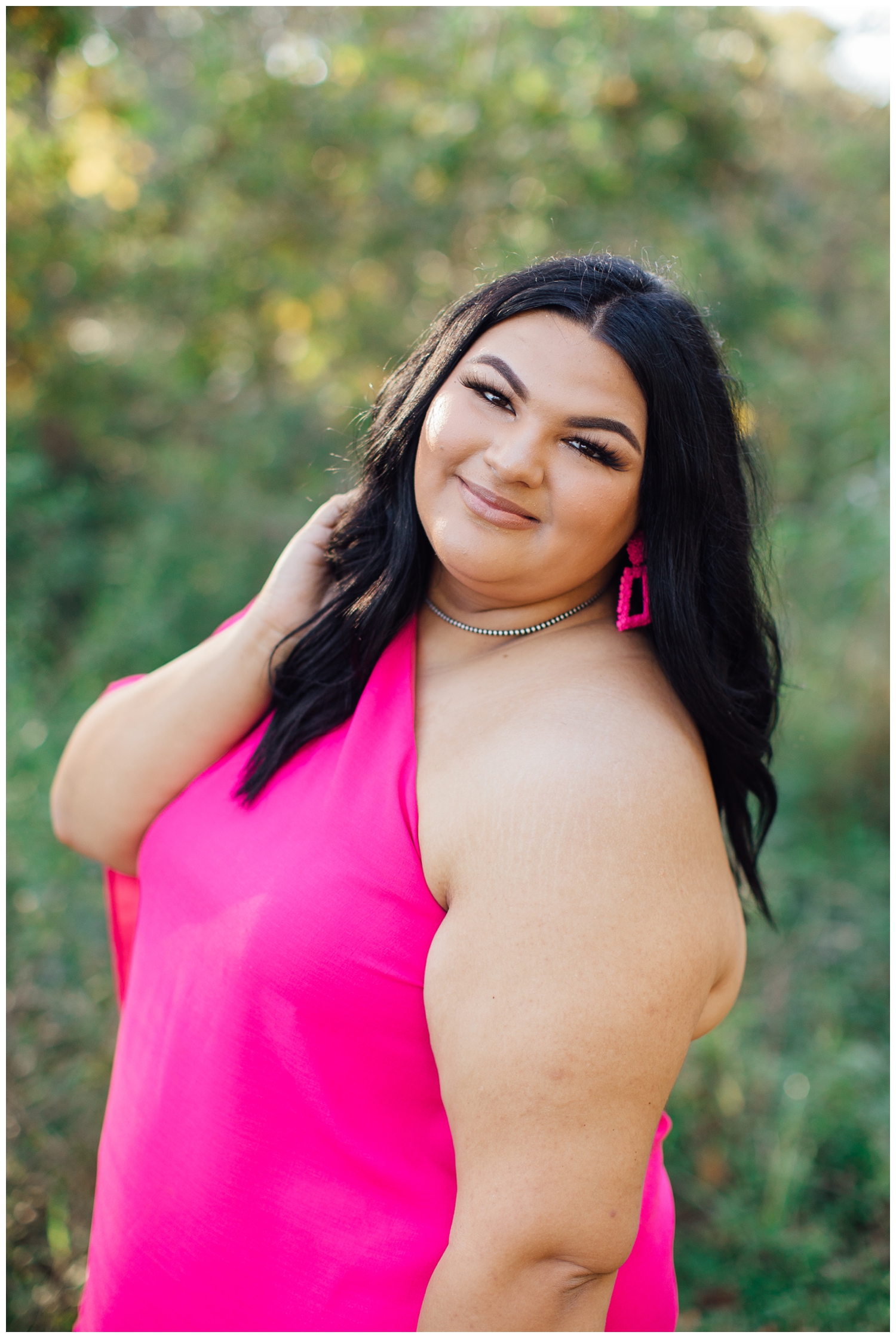 girl in hot pink dress with hand in hair for senior photographer in Cypress Texas