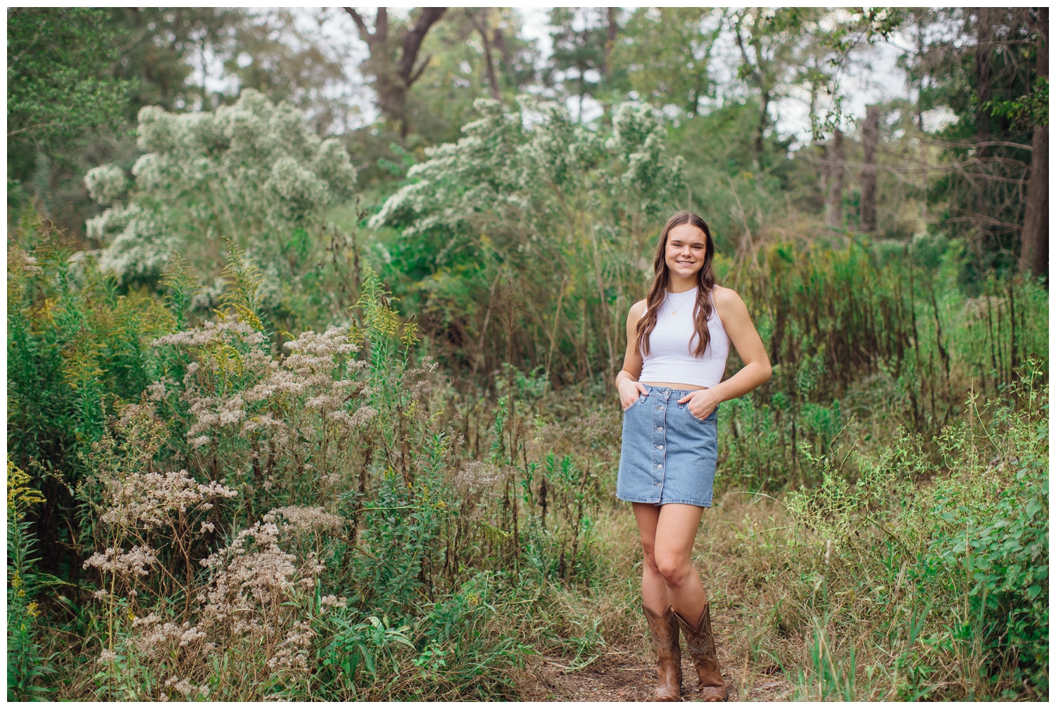 girl in cowboy boots, denim skirt, white shirt standing in a Houston field