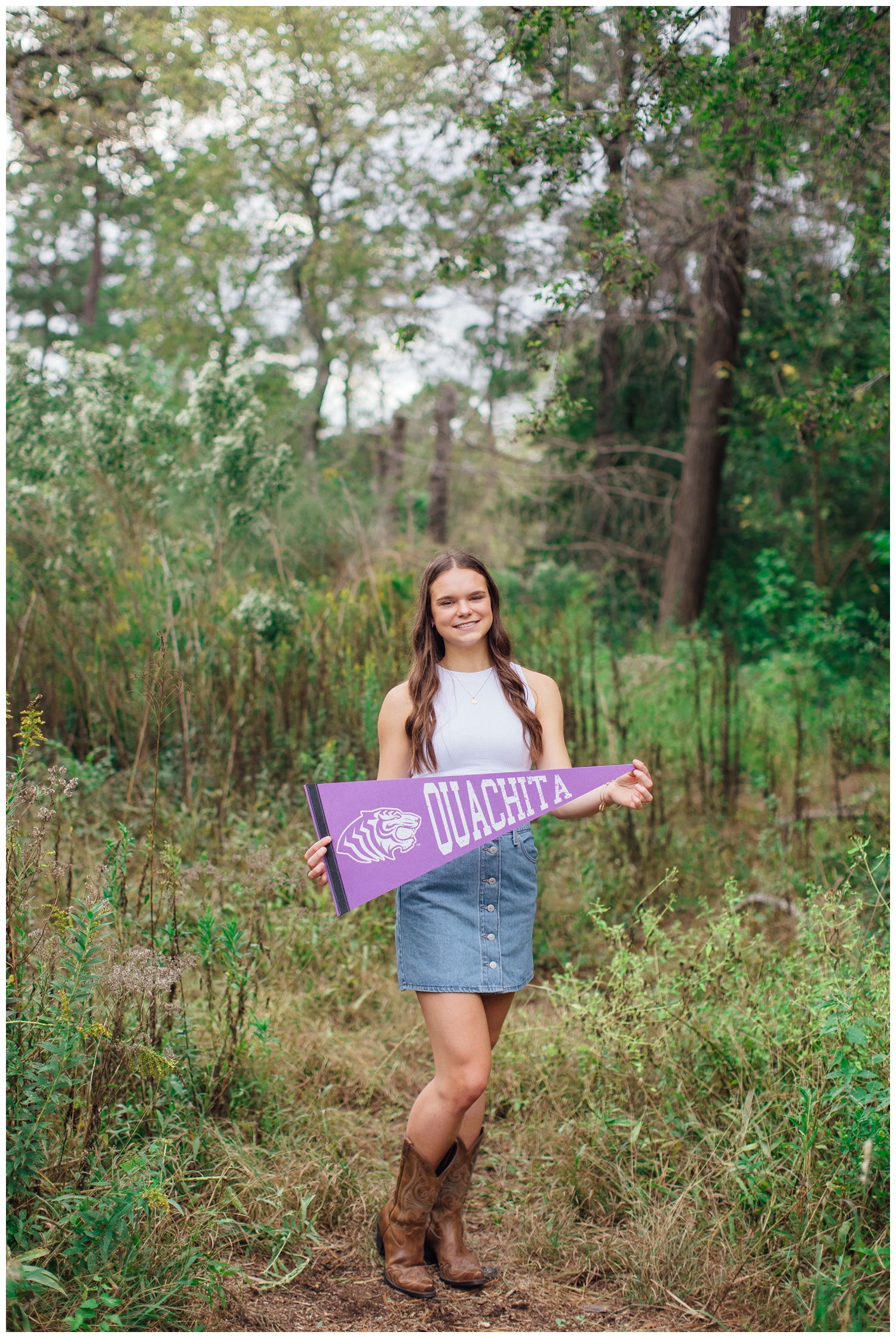 senior girl in white shirt and denim skirt holding purple college flag