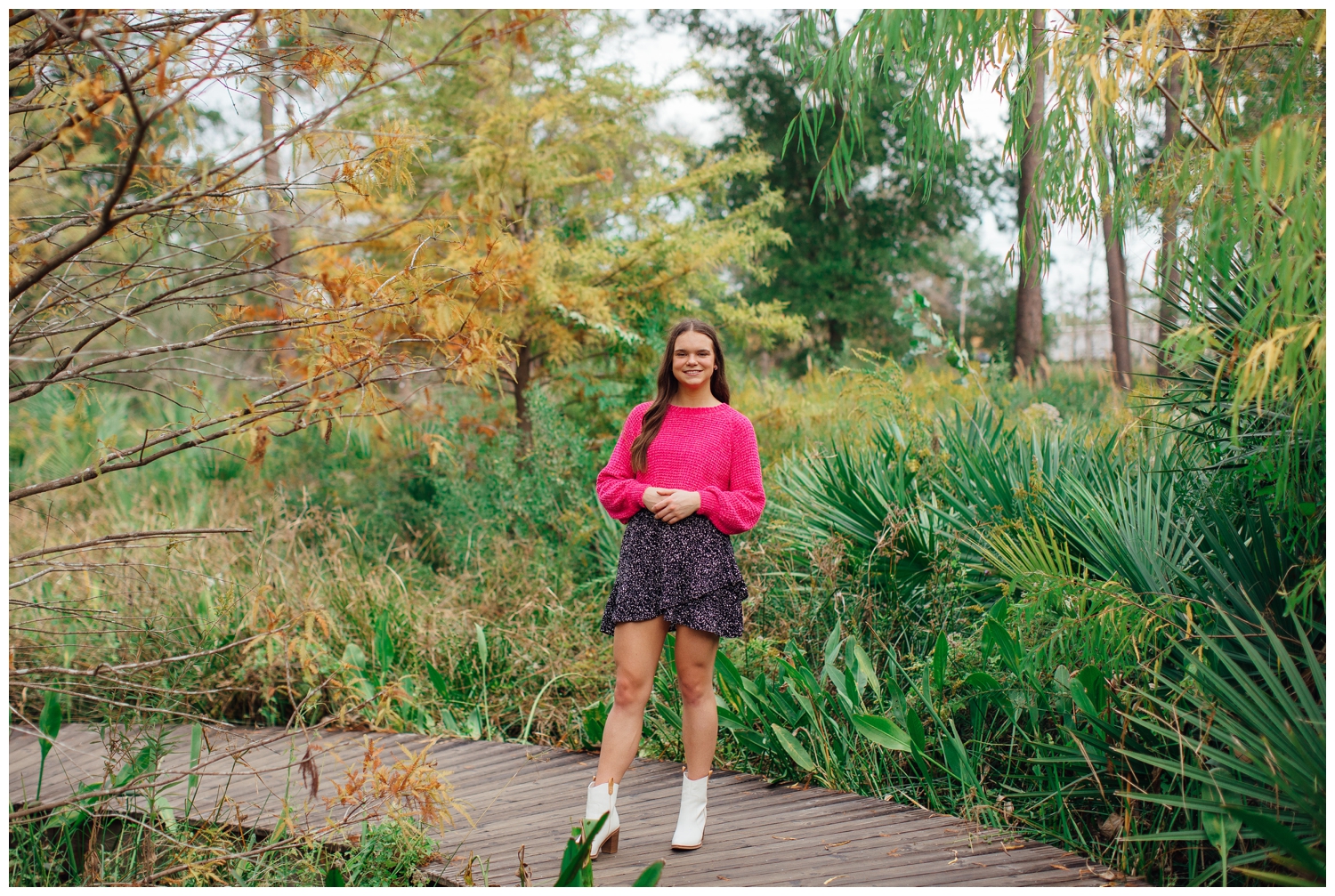 girl in pink shirt, black skirt and white boots standing outdoors at Houston Arboretum