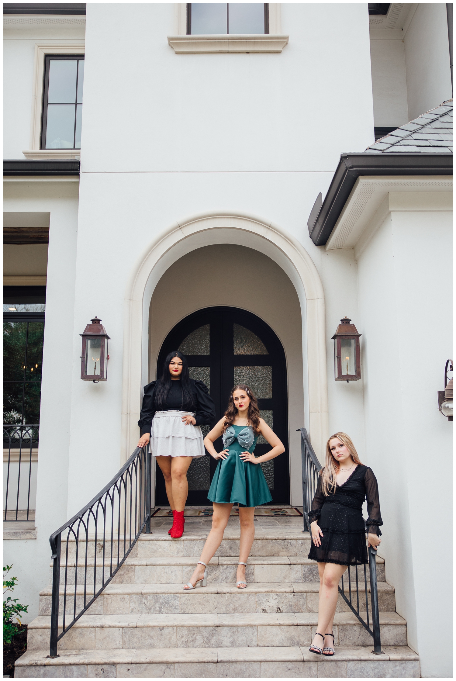 three senior girls standing on steps in front of white stucco house for senior reps Christmas photoshoot