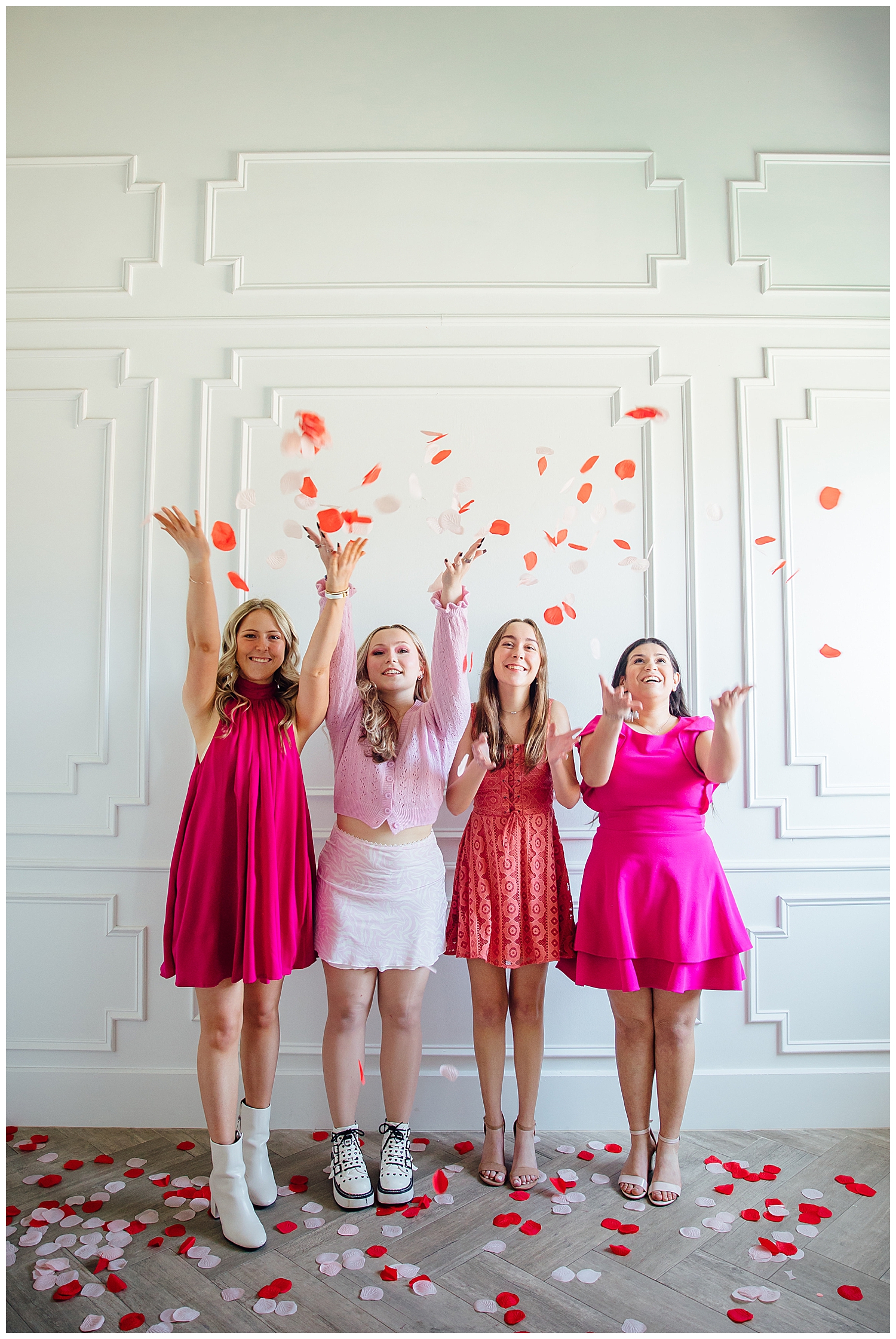 four girls in pink and white tossing rose petals