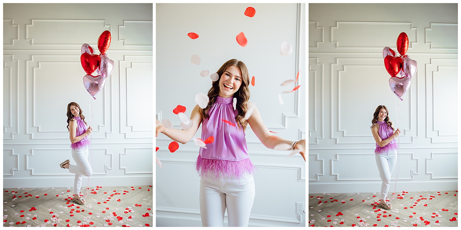 high school girl in white pants purple shirt throwing rose petals for Valentine's Day Senior Photoshoot